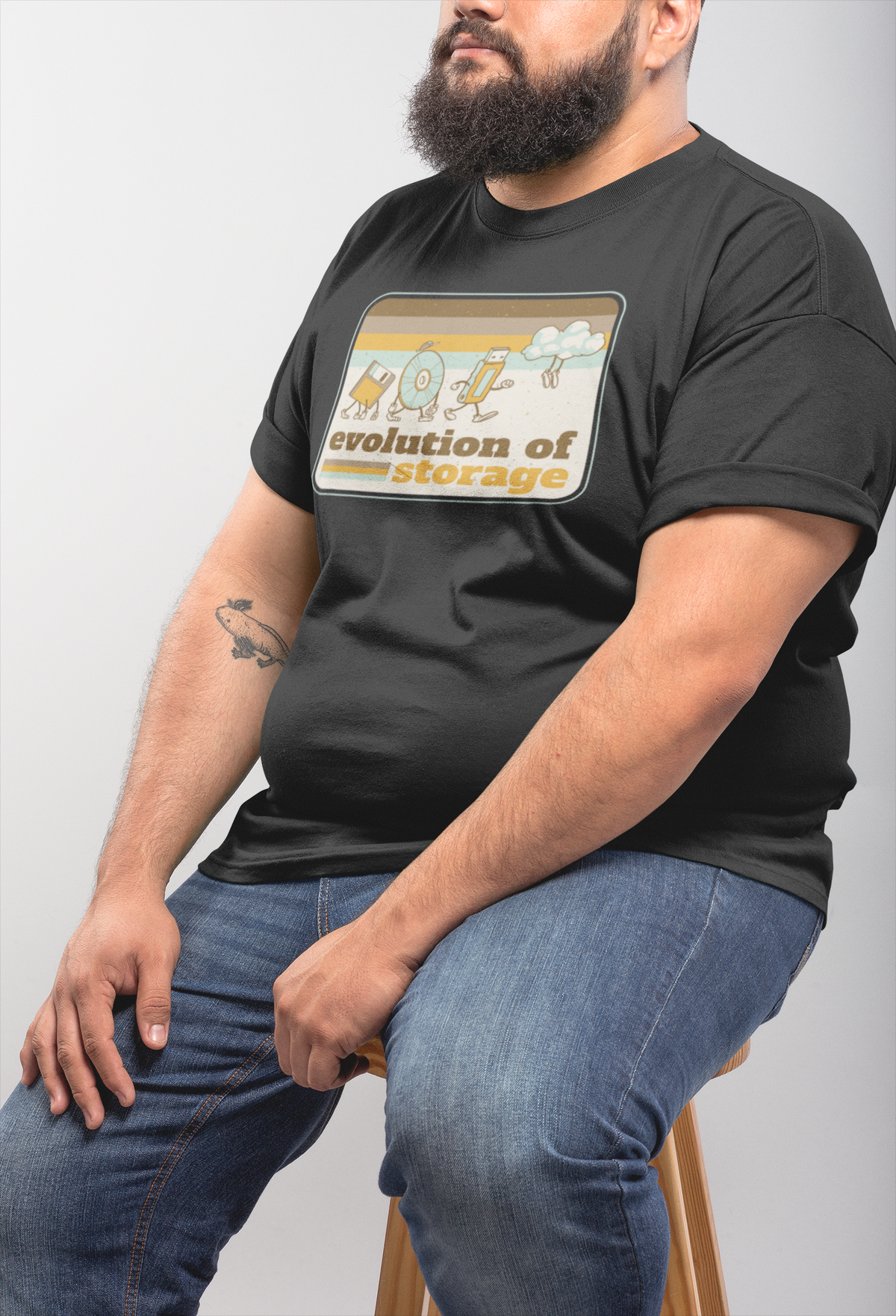 'Evolution of Storage' t-shirt in black, heavyset man model seated wearing it, funny gift for tech nerds