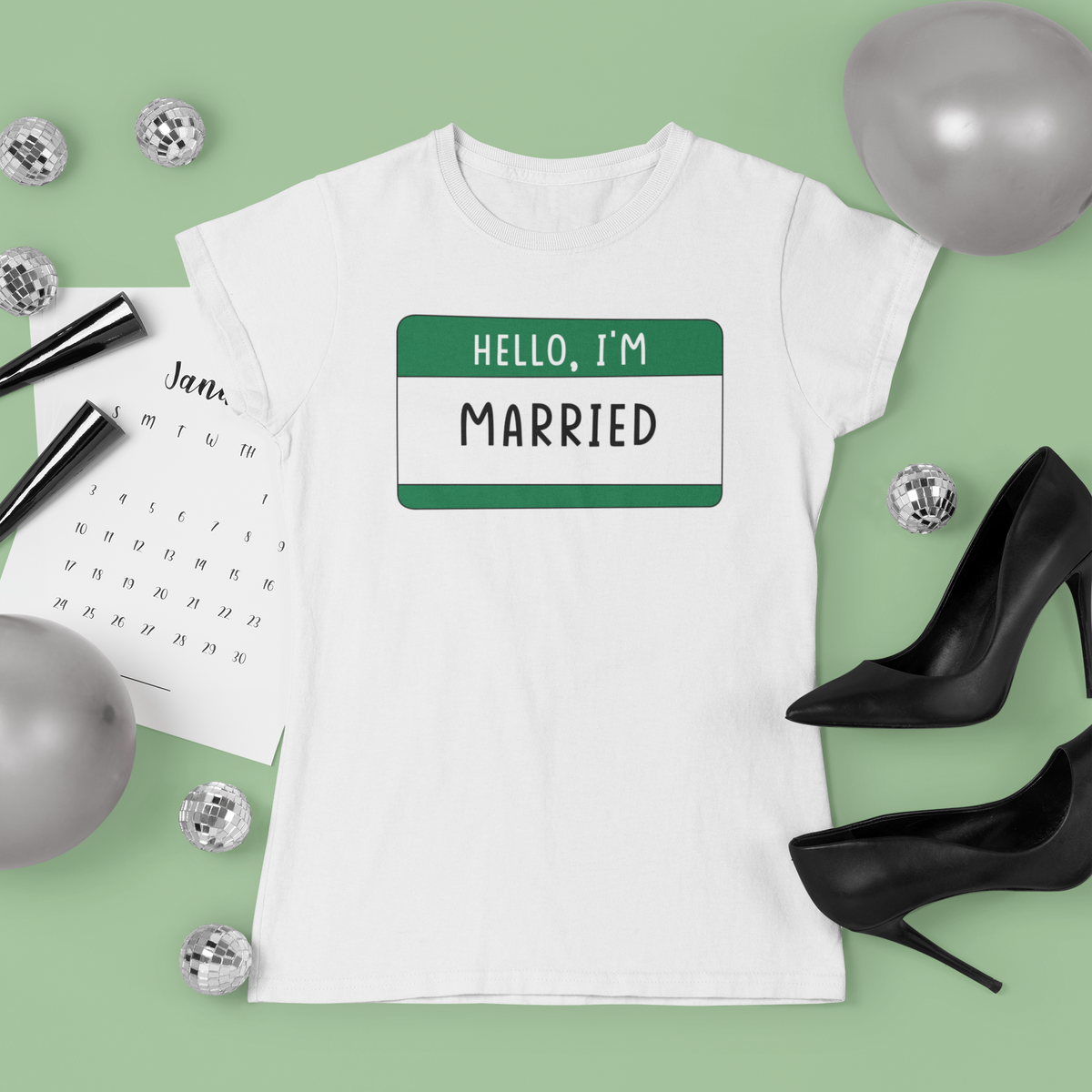 Hello I'm Married name tag T-shirt in white, flat lay styled with heels and balloons, funny wedding tee