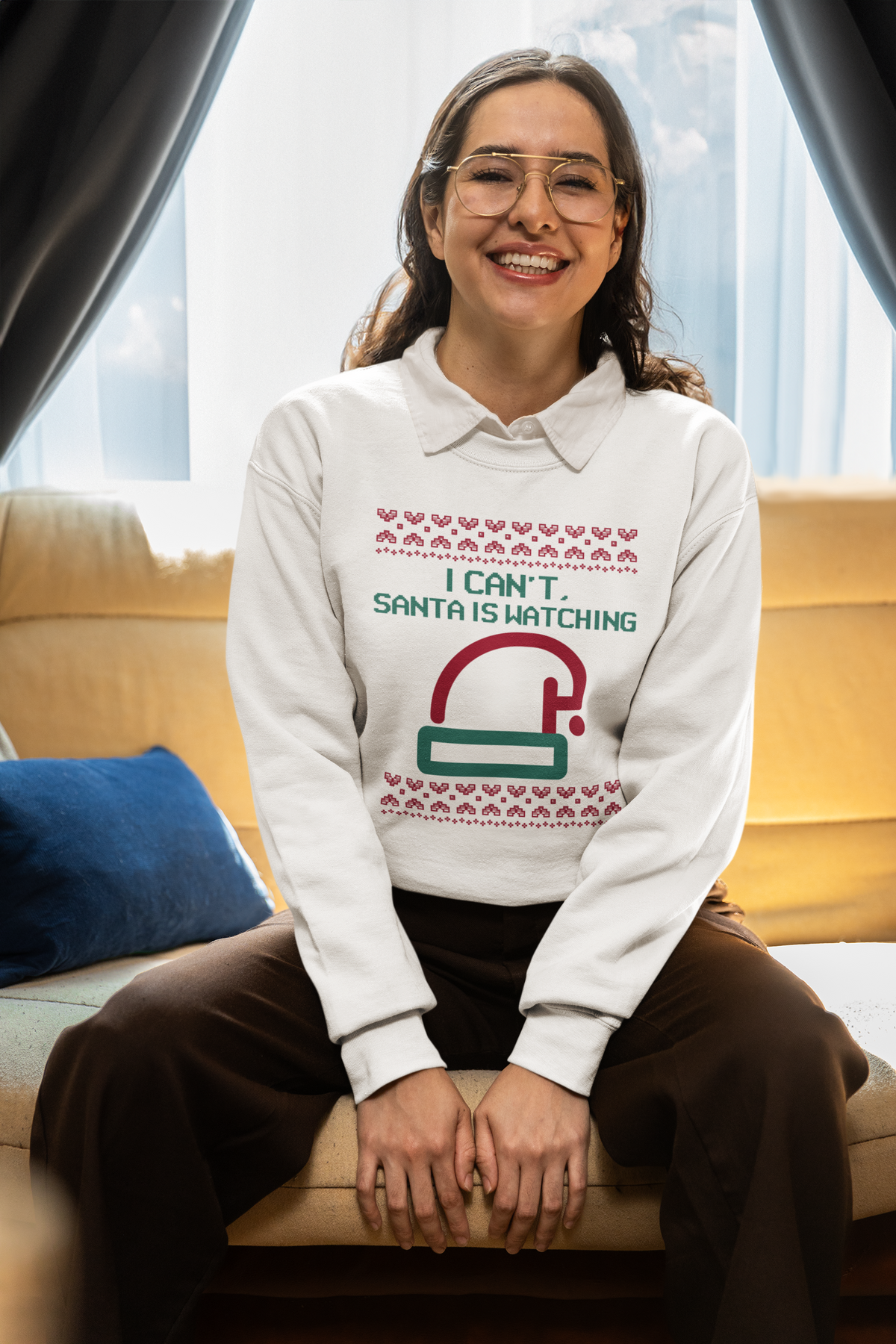 'I Can't Santa Is Watching' camera graphic sweatshirt in white, woman wearing it seated indoors, funny Christmas gift