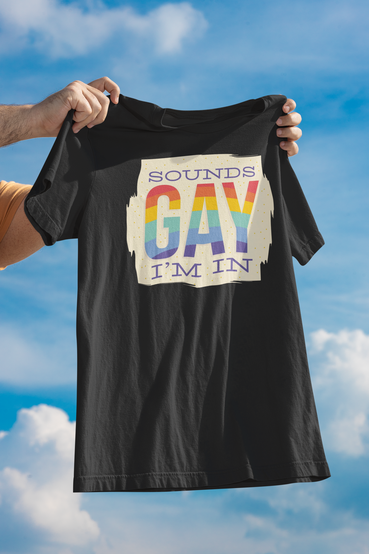 'Sounds Gay I'm In' T-shirt in black, held up outdoors against a blue sky, funny gay pride gift