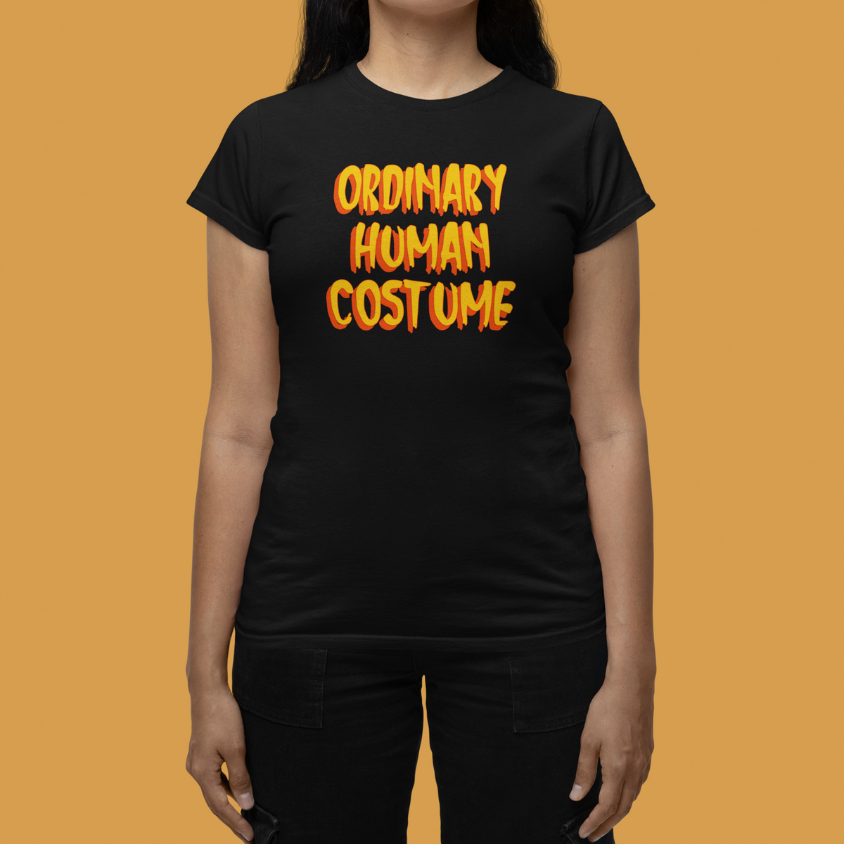 'Ordinary Human Costume' funny halloween t-shirt in black, woman wearing it orange background, gift