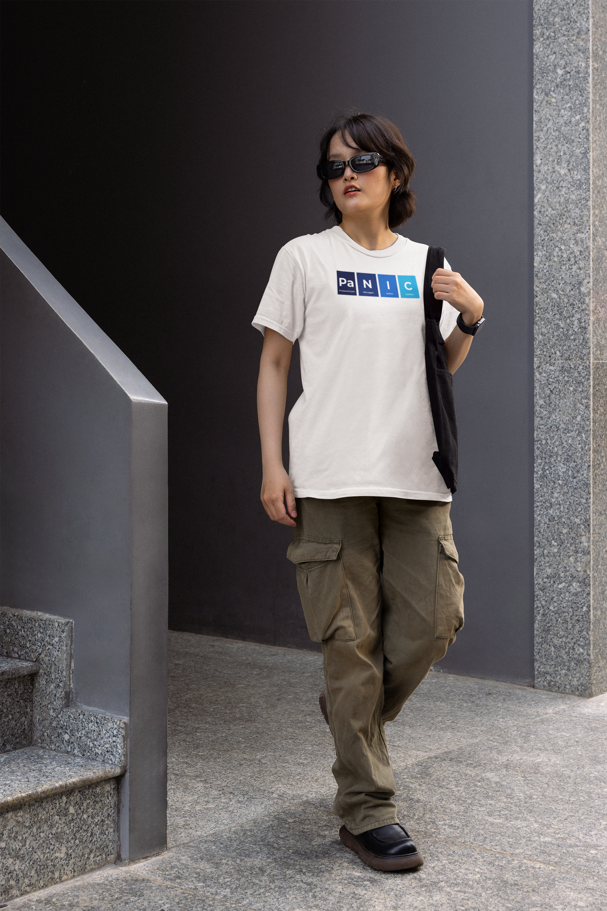 'Pa-N-I-C' periodic table women's tee in white, woman walking outdoors, casual streetwear photo