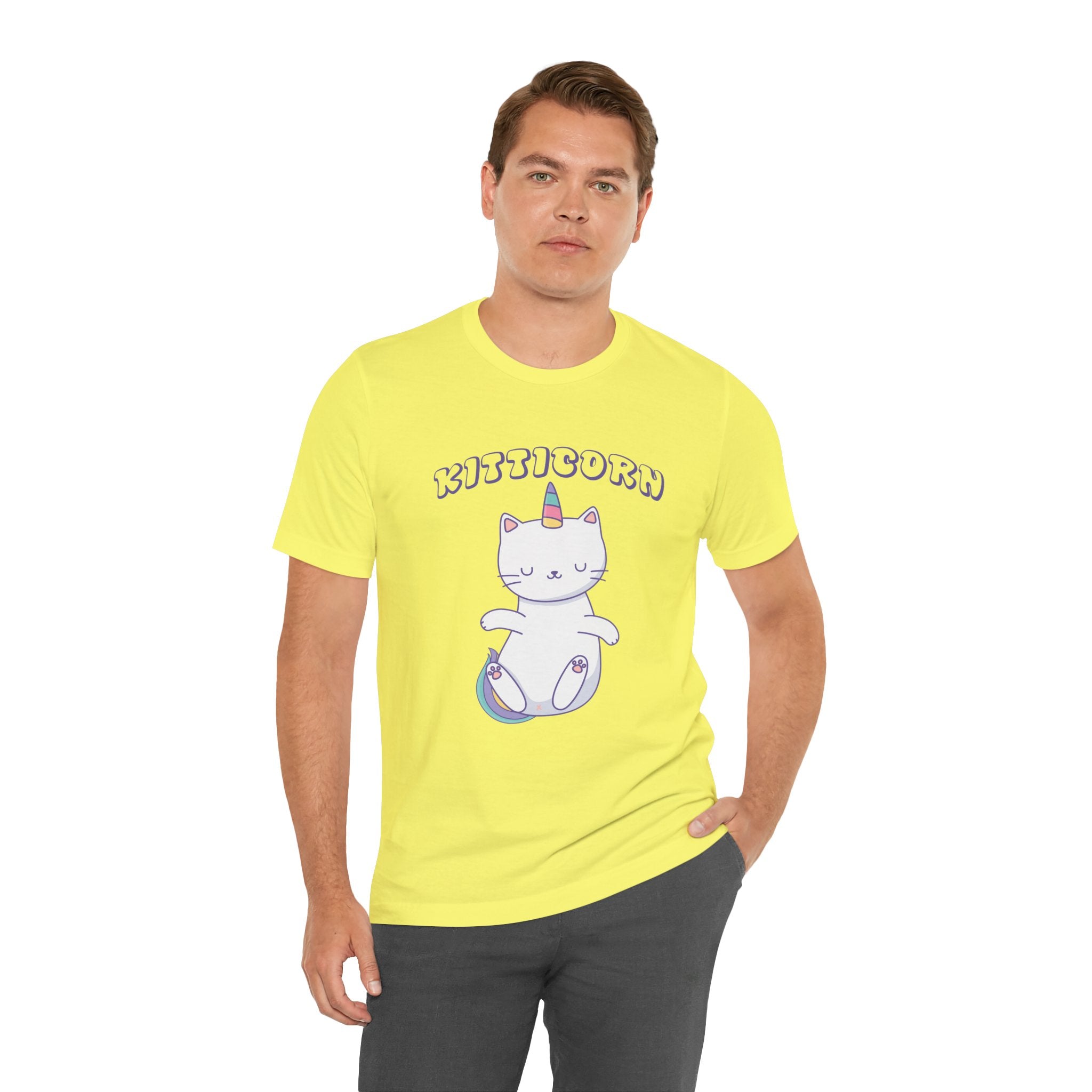 A man wears the Kitticorn tee, showcasing a yellow shirt with a cartoon cat-unicorn and "Kitticorn" above the graphic, fusing playful pop culture with whimsical unicorn charm.