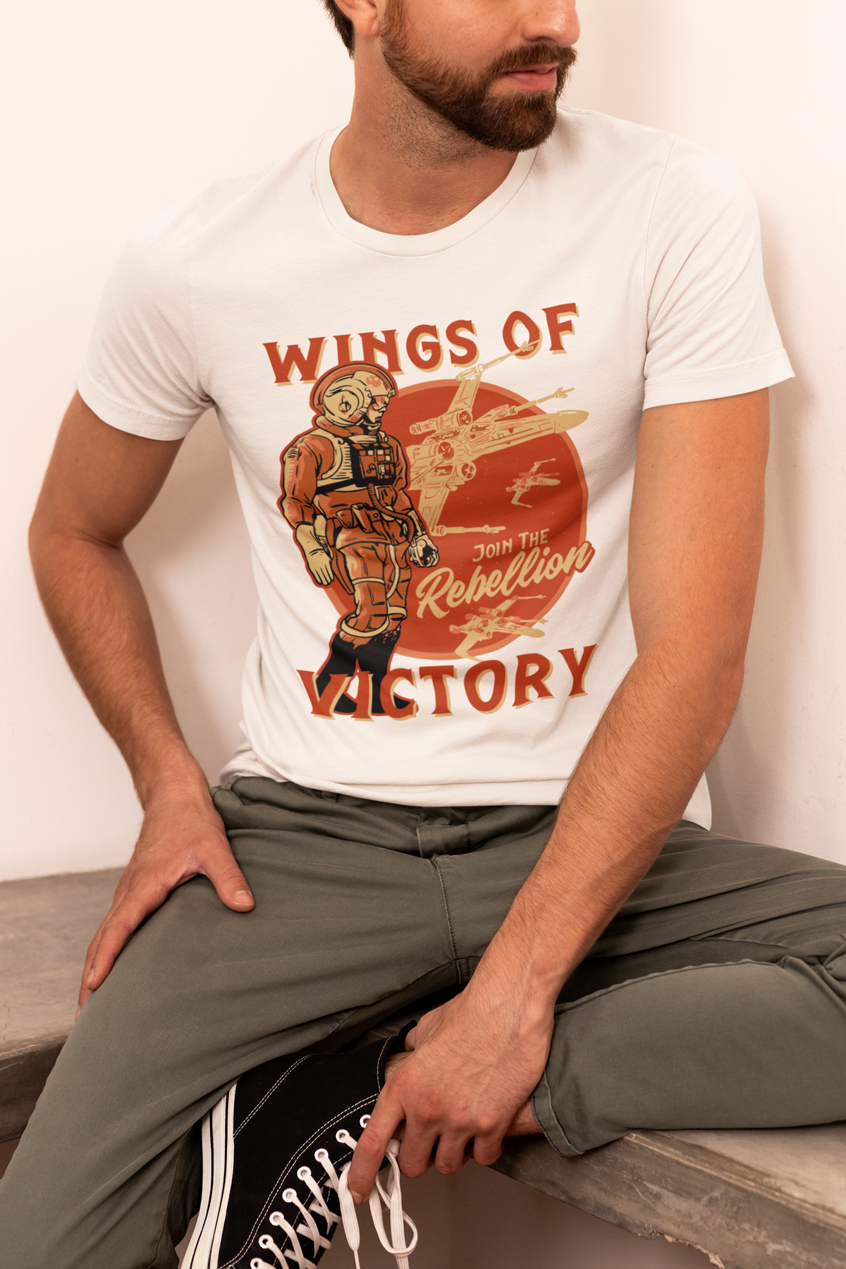 'Wings of Victory' rebellion t-shirt in white, bearded man sitting wearing it, sci-fi fan gift