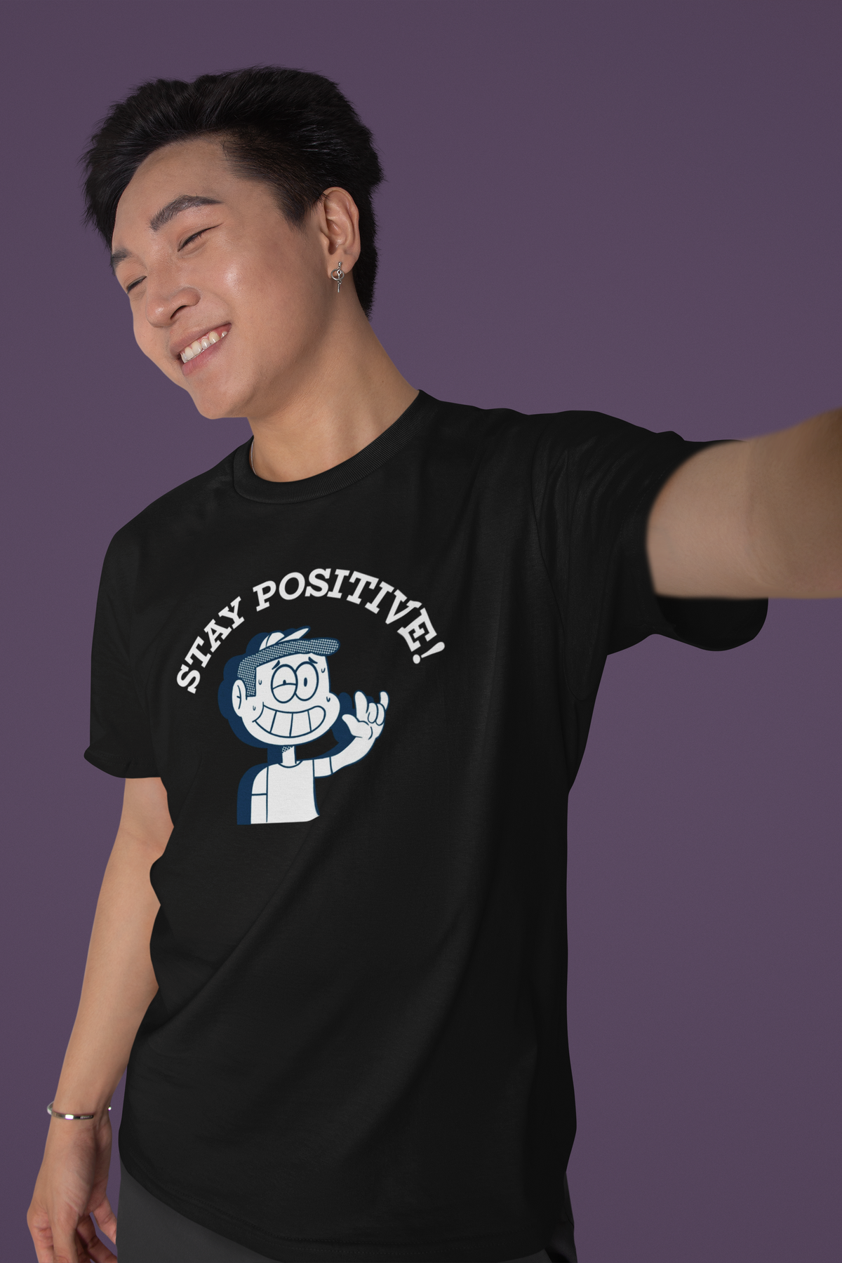'Stay Positive' cartoon graphic t-shirt in black, man wearing it, purple backdrop, funny pun gift