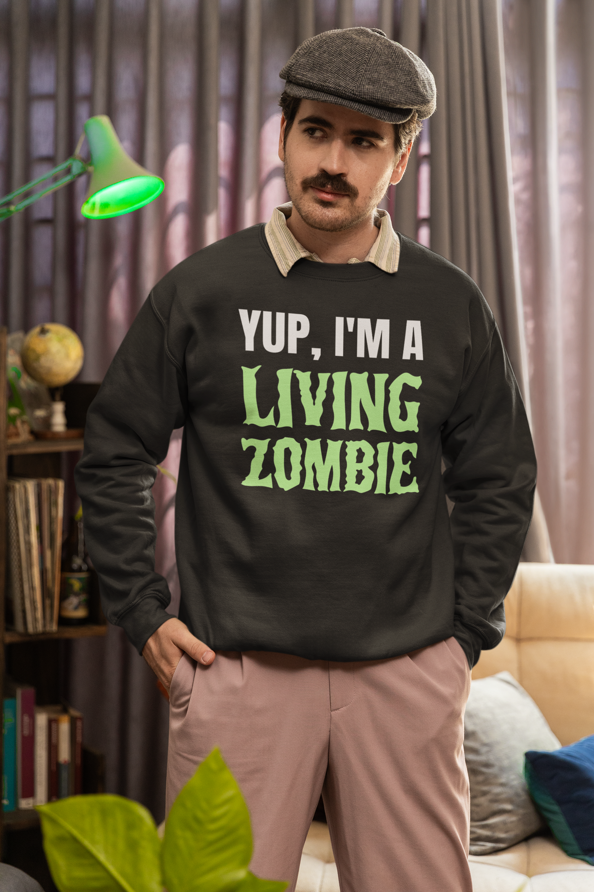 'Yup, I'm a Living Zombie' sweatshirt in black, mustached man wearing it at home, funny zombie gift
