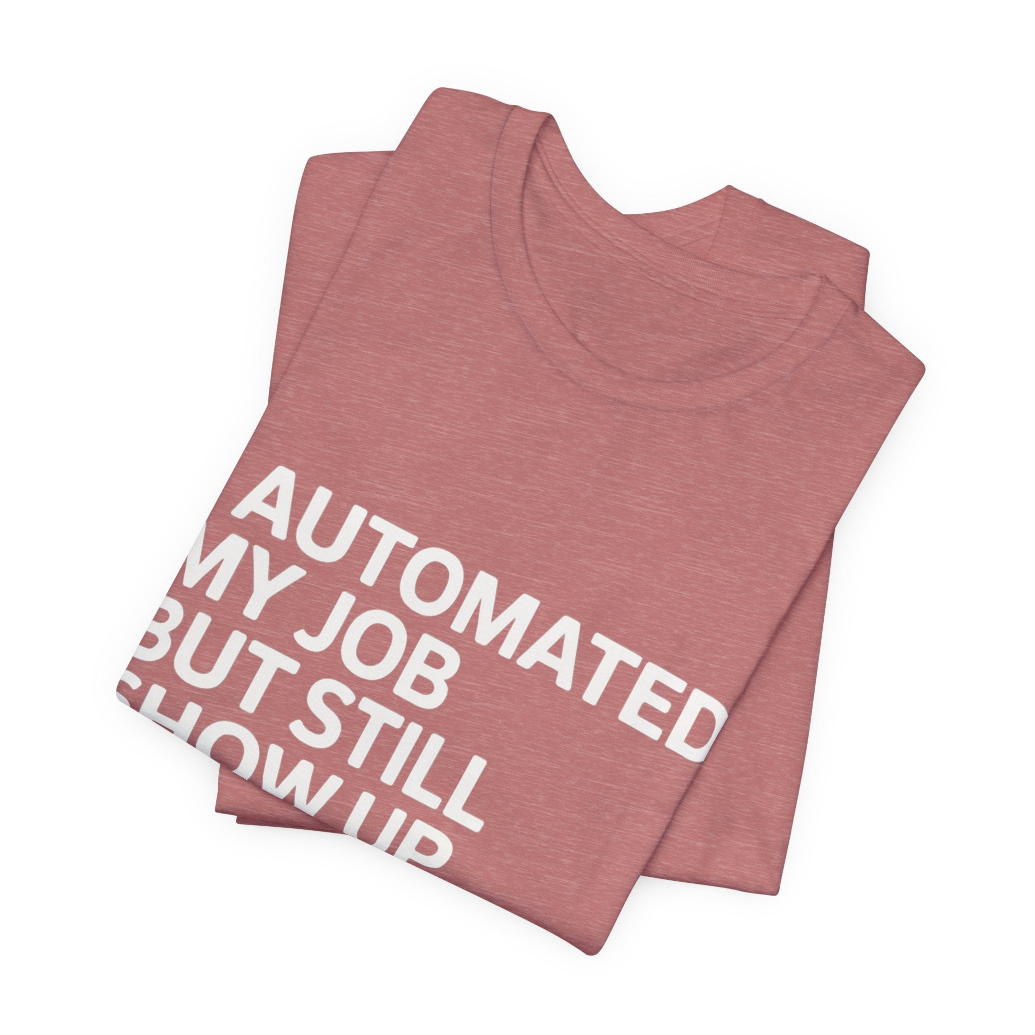 A folded pink t-shirt named "I Automated My Job But Still Show Up for the Meetings," featuring bold white textāan ideal tech humor shirt for coders.