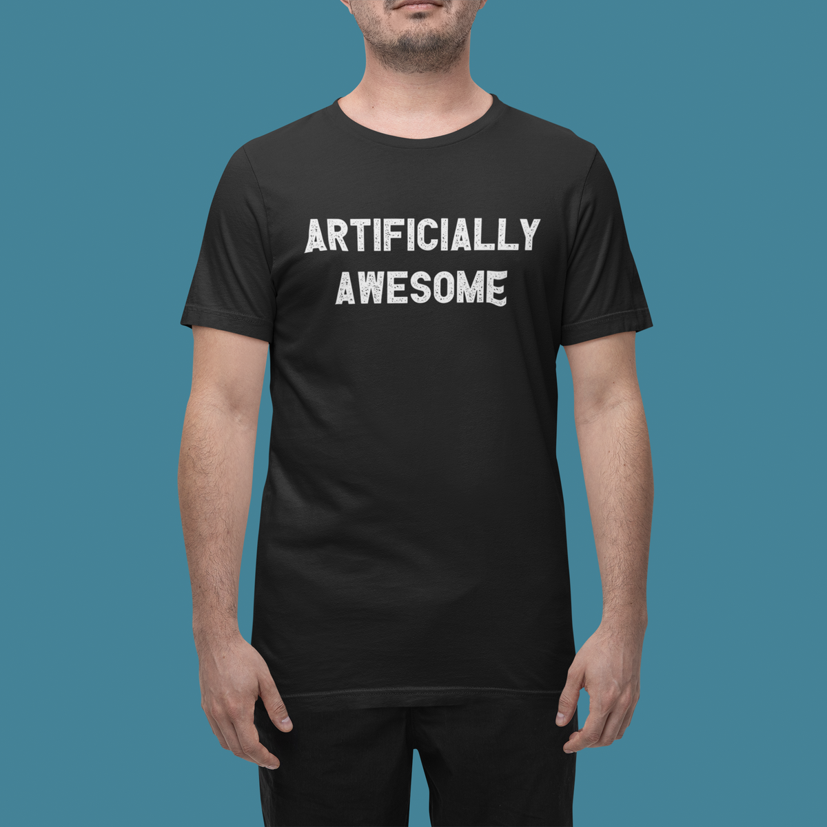 'Artificially Awesome' t-shirt in black, close-up on man wearing it, teal background, funny AI shirt