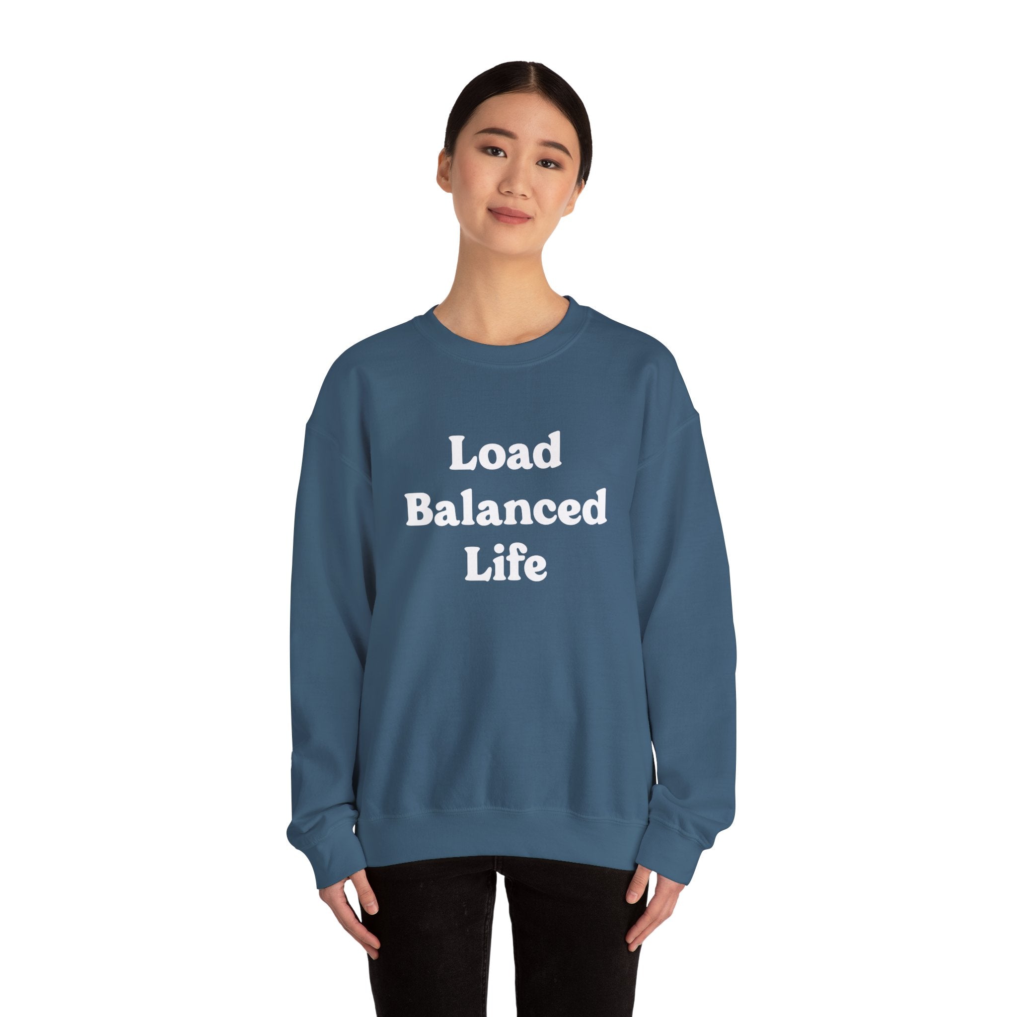 A person stands smiling in a Load Balanced Life sweatshirt, radiating cozy comfort in its teal hue.