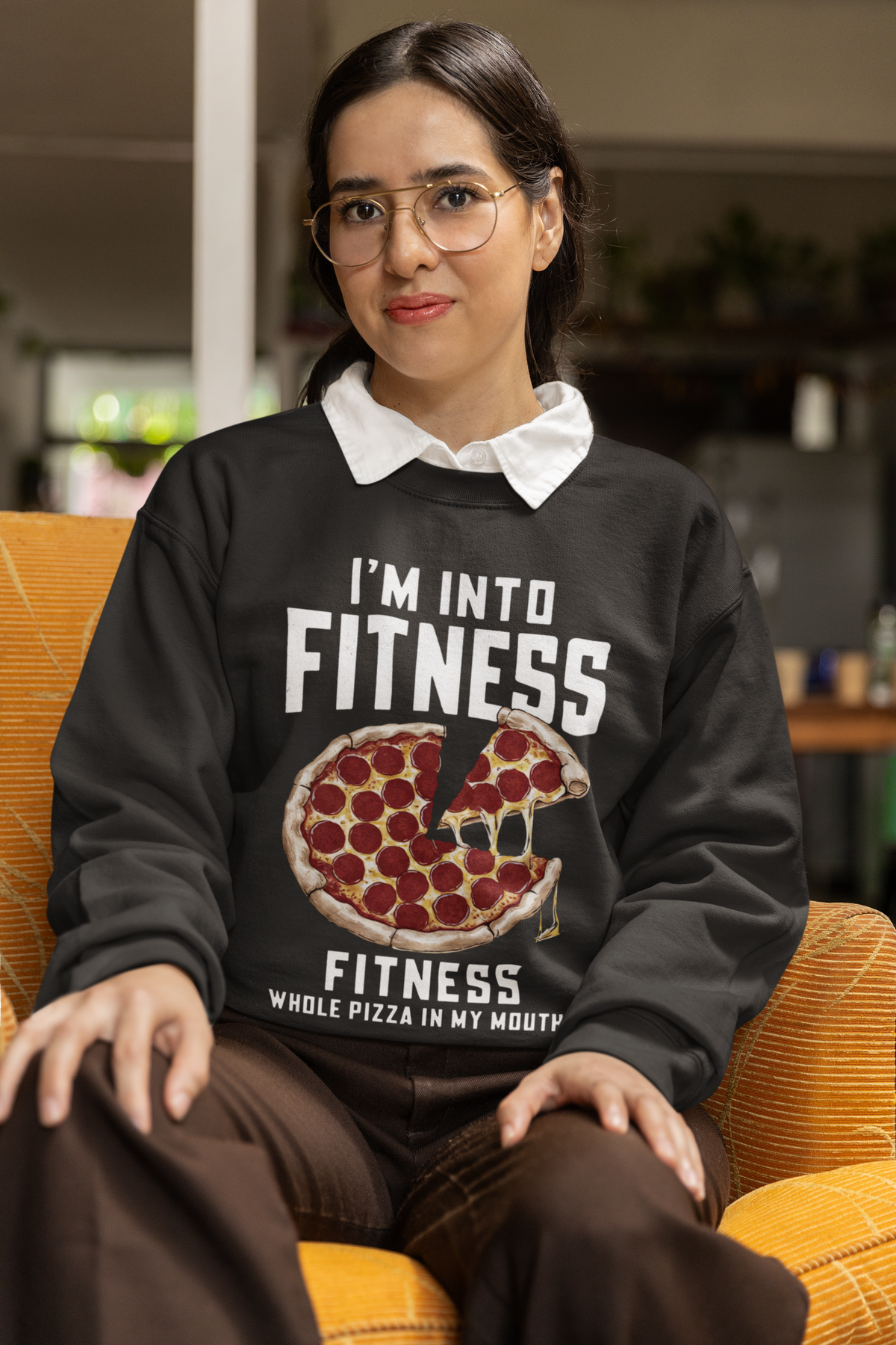 'I'm Into Fitness' pizza sweatshirt in black, woman sitting indoors wearing it, funny foodie gift idea