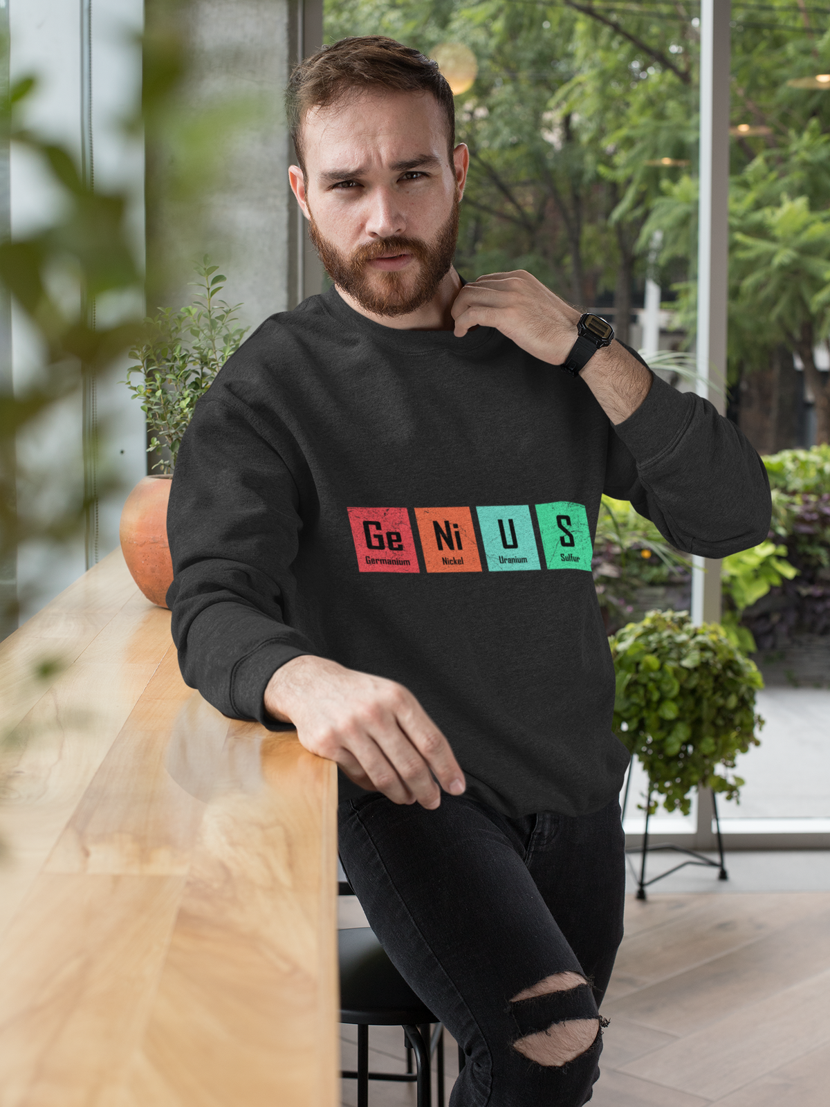 'Genius' periodic table pun sweatshirt in black, bearded man indoors, funny chemistry gift for him