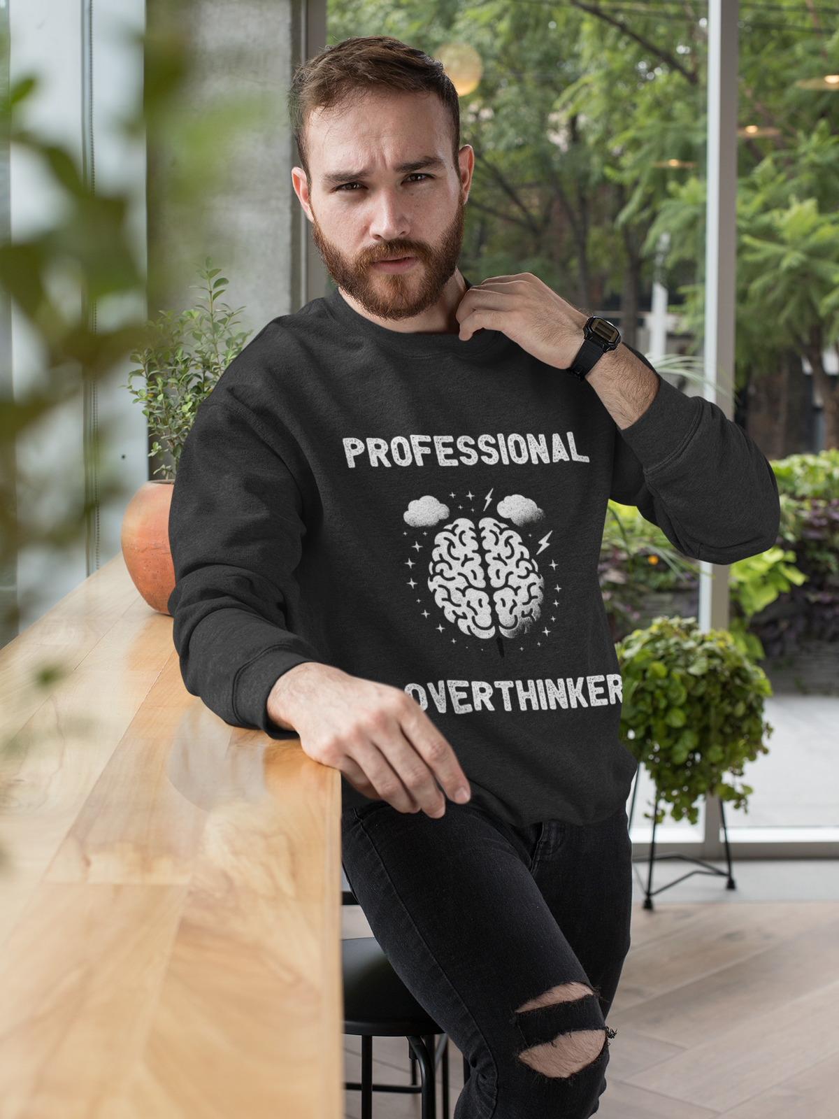 "Professional Overthinker" sweatshirt in black, man wearing it indoors, funny gift for overthinkers