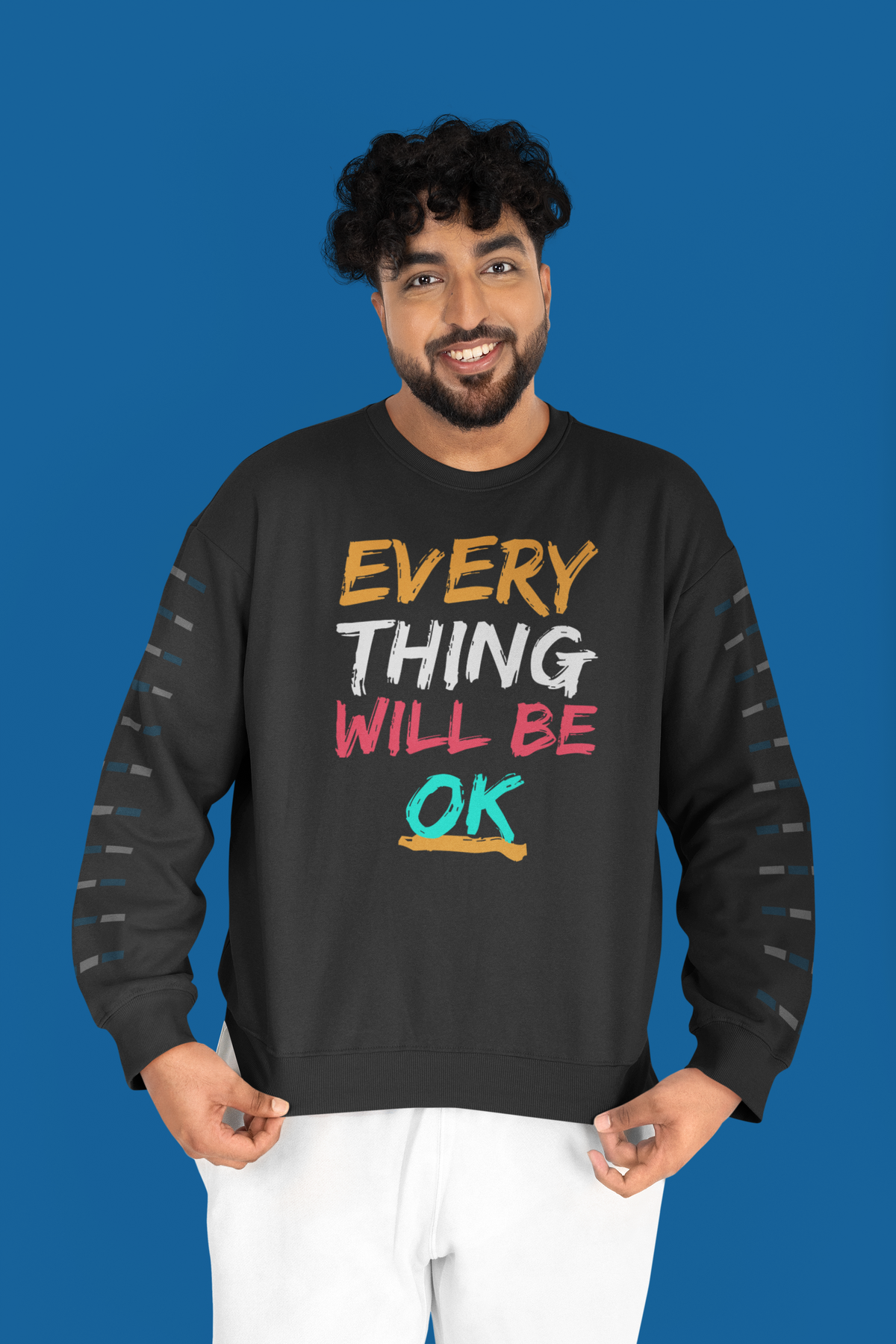 'Everything Will Be OK' sweatshirt in charcoal, man wearing it against a blue backdrop, uplifting gift