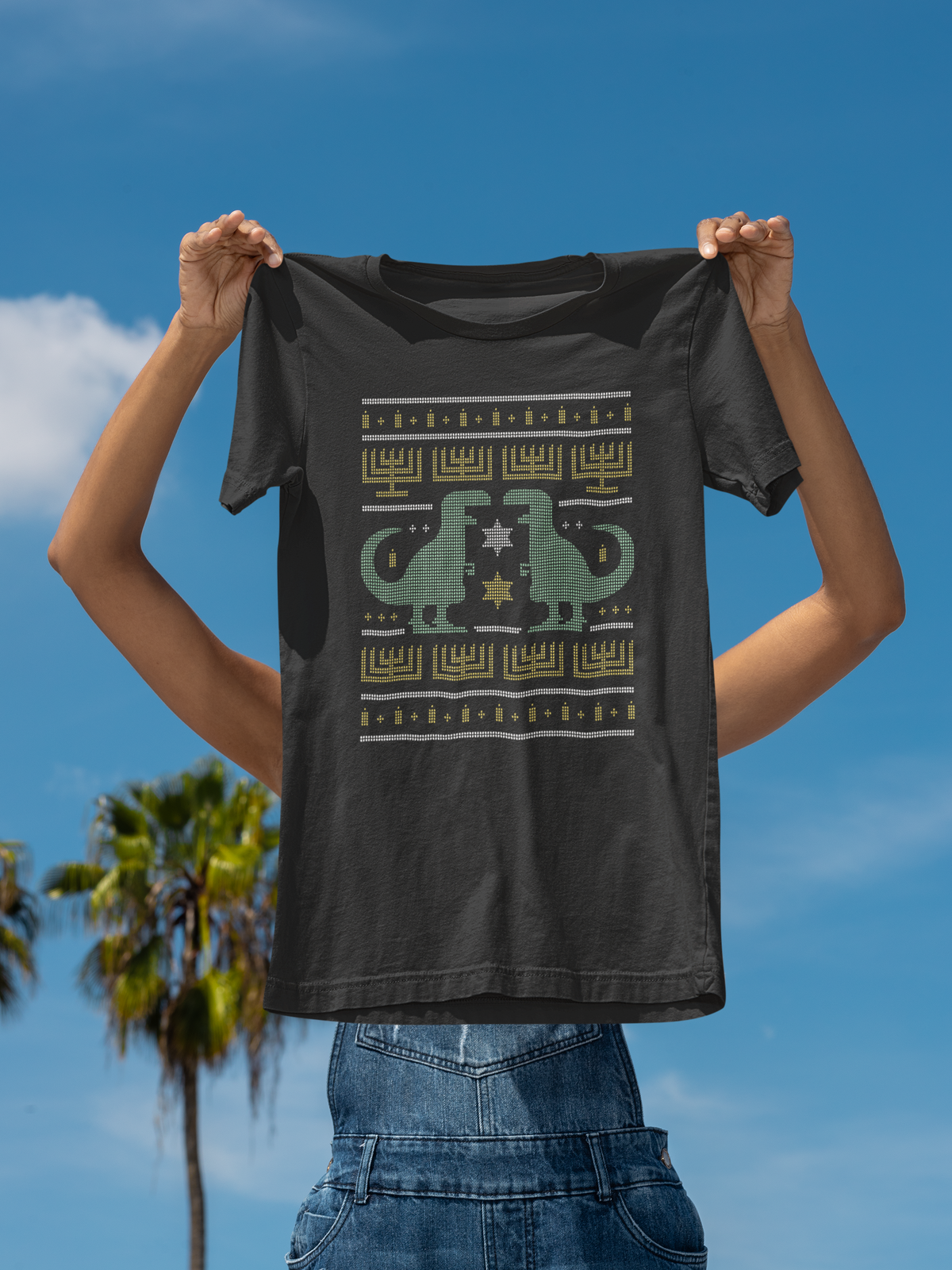 Dino Ugly Sweater T-shirt in charcoal, held up against a blue sky, funny holiday dinosaur gift