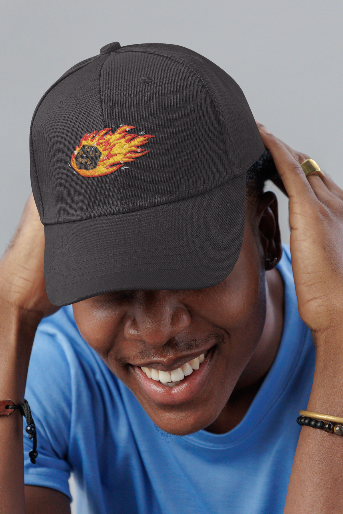Polyhedral Dice On Fire embroidered D&D dad hat, smiling man in a studio, lifestyle mockup, Geekpsters