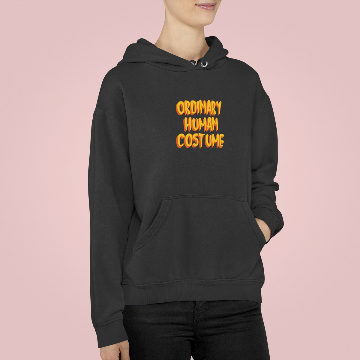 'Ordinary Human Costume' funny halloween hoodie in black, woman wearing it, pink background, funny gift