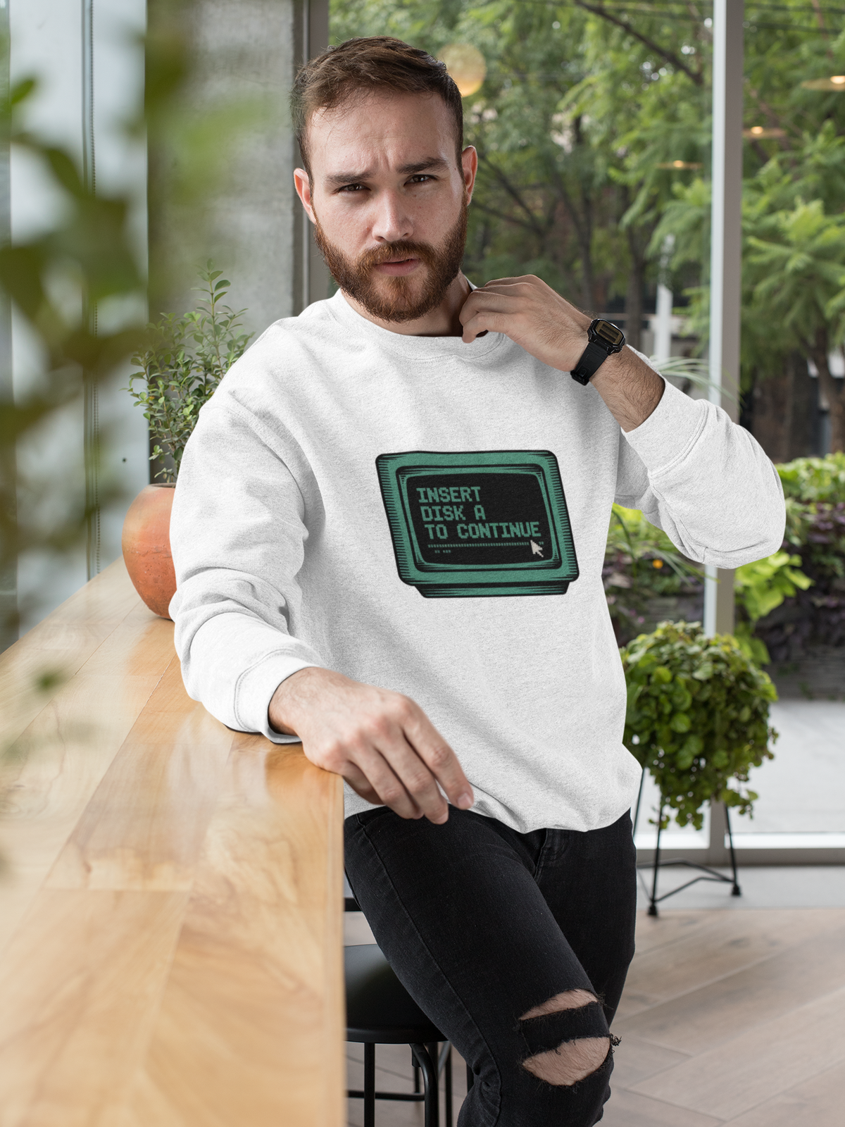 'Insert Disk A to Continue' sweatshirt in white, bearded man wearing it in office, retro gamer nostalgia gift