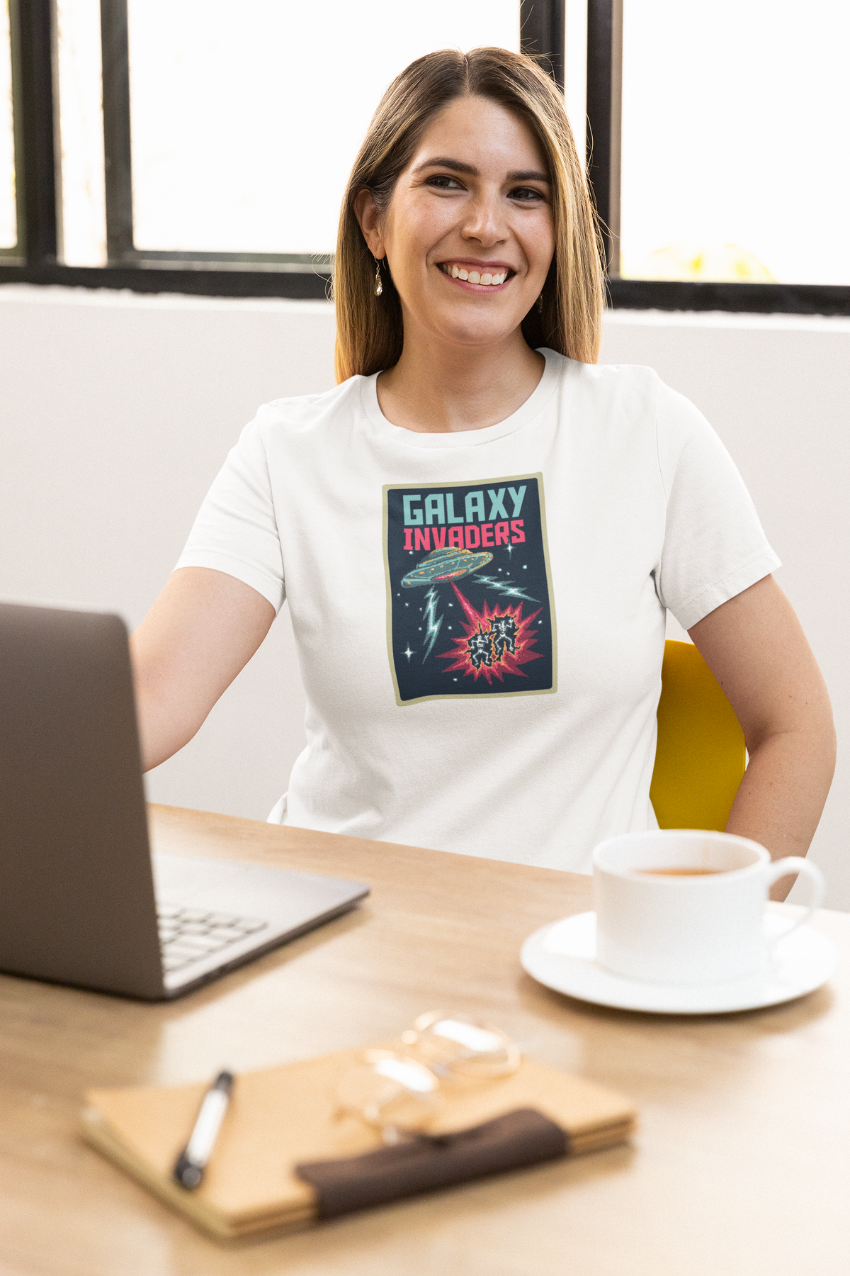 'Pixel Galaxy Invaders' t-shirt in white, woman wearing it at an office desk, T-Shirt mockup, Geekpsters