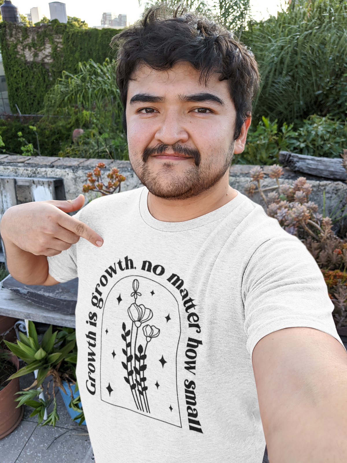 'Growth Is Growth No Matter How Small' t-shirt in white, man pointing at it outdoors