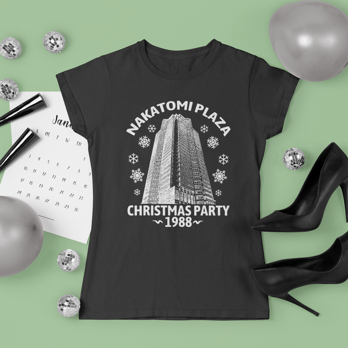 'Nakatomi Plaza Christmas Party 1988' t-shirt in black, flat lay with festive decor, holiday gift