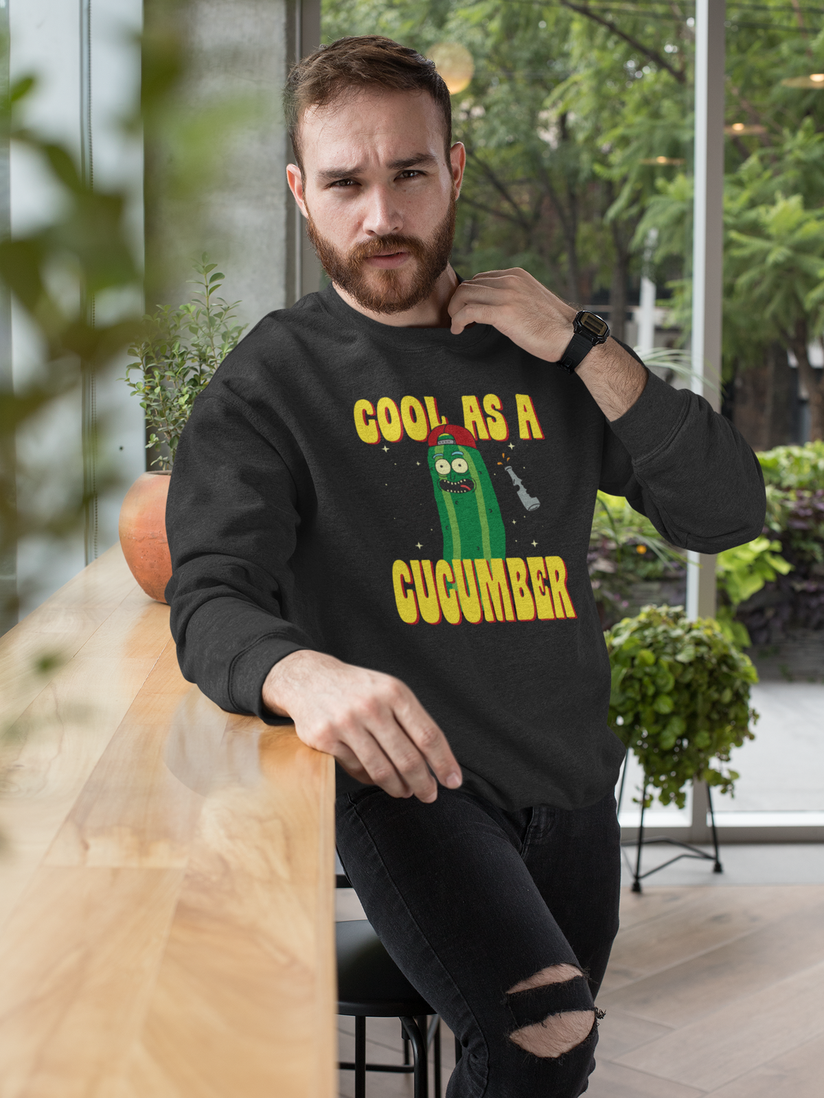 "Cool As A Cucumber" cartoon graphic sweatshirt in black, bearded man wearing it in the city, funny pun gift for him