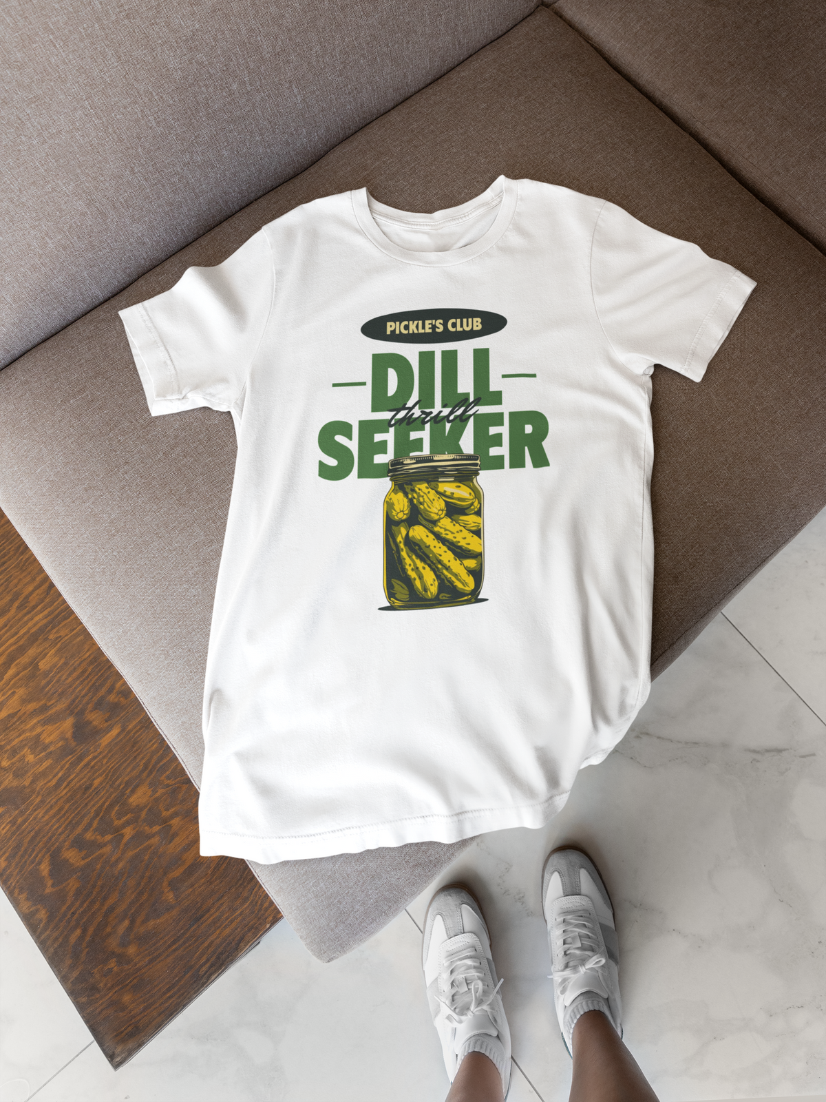 'Dill Seeker' pickle jar pun t-shirt in white, flat lay on a wood floor, funny gift for foodies