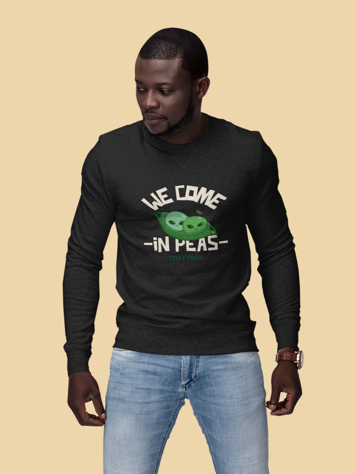 'We Come in Peas' alien pea sweatshirt in black, man wearing it against a yellow backdrop, funny sci-fi pun gift