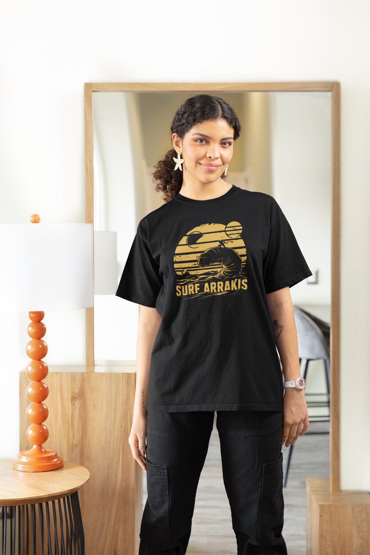 Surf Arrakis sandworm t-shirt in black, woman wearing it indoors near a mirror, funny sci-fi surf gift
