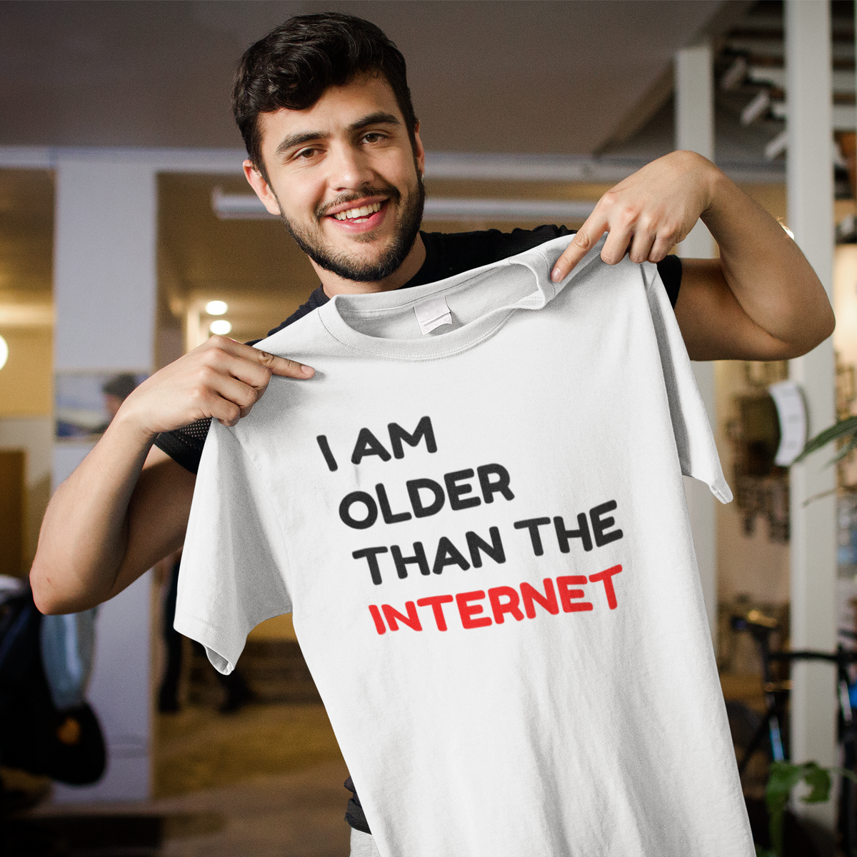 'I Am Older Than The Internet' t-shirt in white, smiling man holding it up indoors, funny retro gift