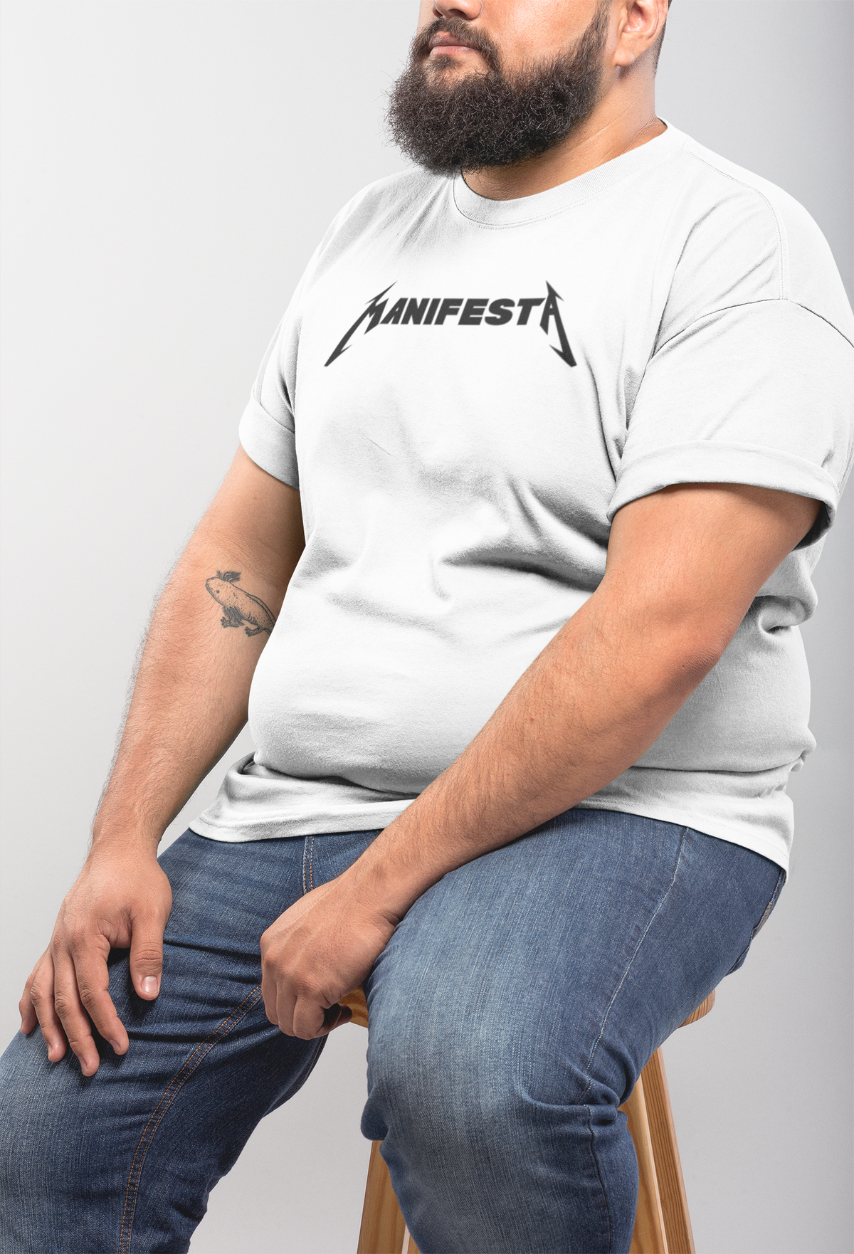 'Manifesta' band logo T-shirt in white, bearded man sitting sideways, casual funny graphic tee
