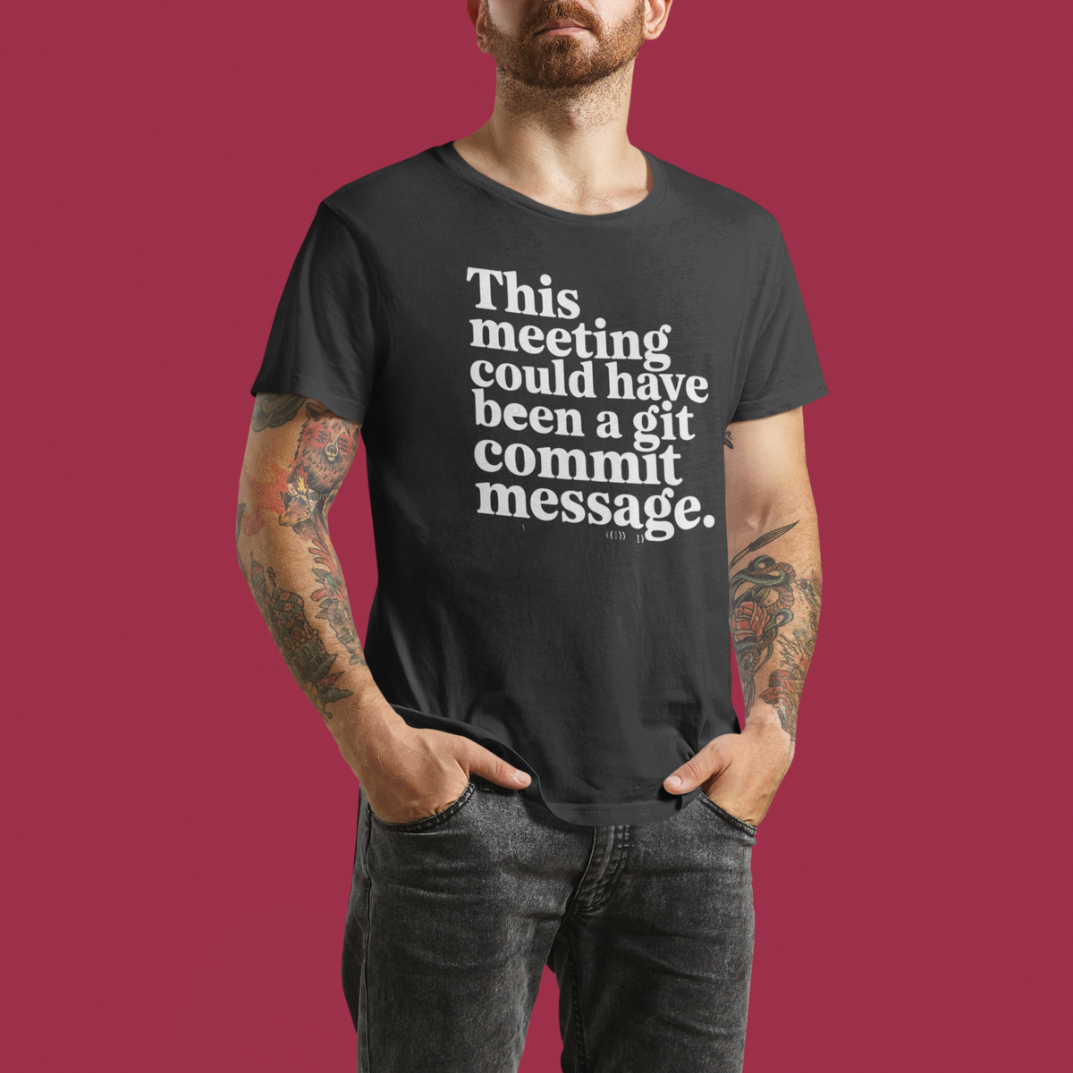 ‘This Meeting Could Have Been a Git Commit Message’ grey tee, man wearing it, red backdrop, funny office shirt