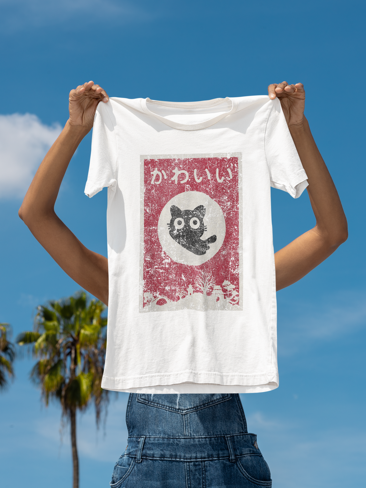 "Kawaii" cat anime poster graphic t-shirt in white, hand holding it up outdoors, cute gift for anime fans
