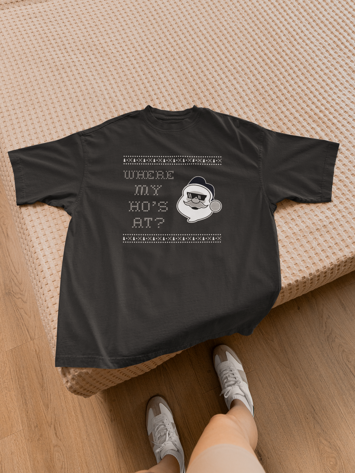 'Where My Ho's At' Santa graphic t-shirt in black, laid flat on bed with sneakers, funny Christmas tee gift