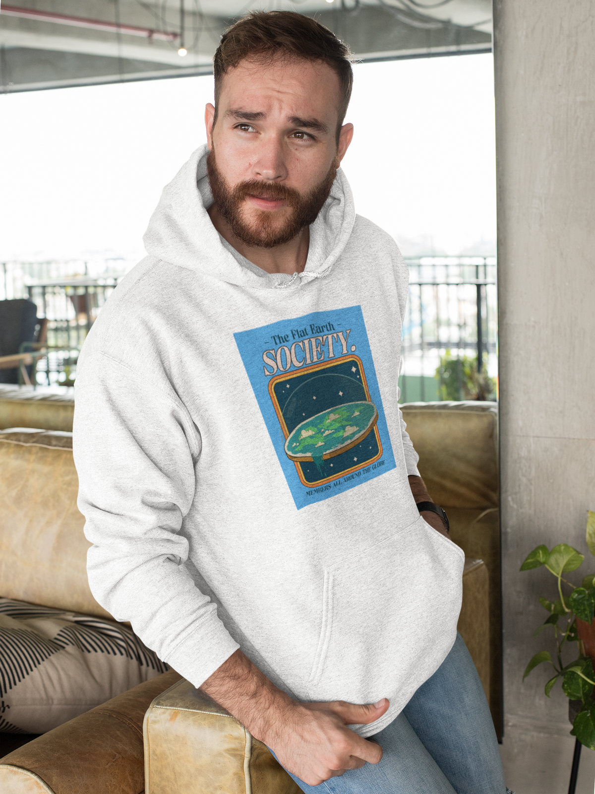 'Flat Earth Society' funny retro badge hoodie in white, bearded man sitting indoors, funny sarcastic gift
