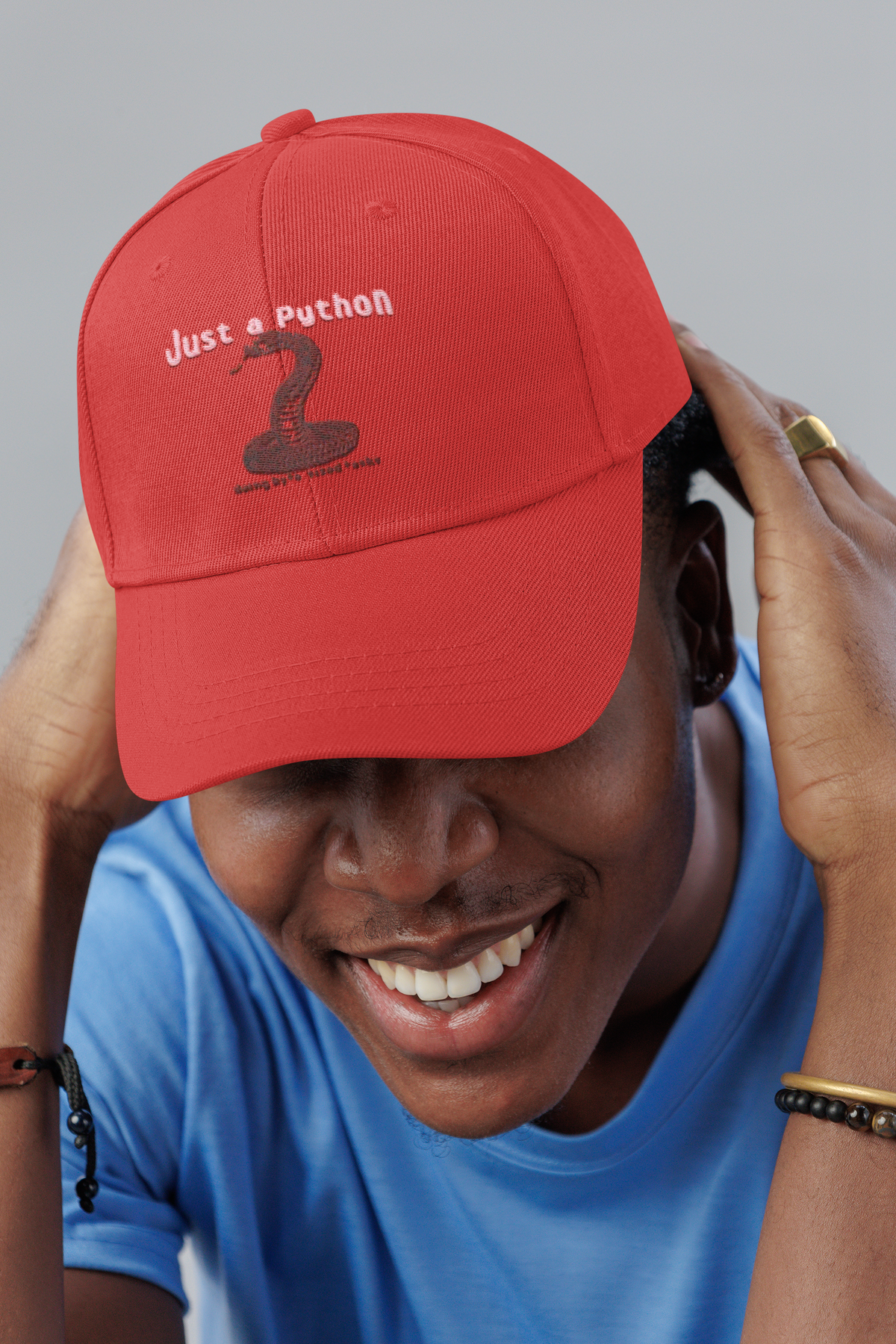 Just a Python embroidered dad hat worn by a smiling man in a studio, lifestyle mockup, Geekpsters