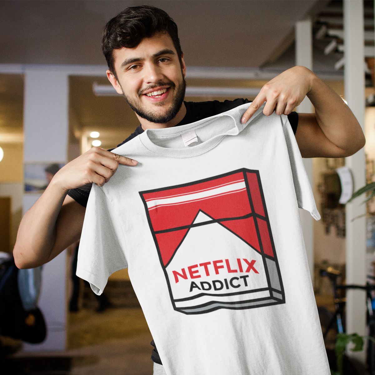 'Netflix Addict' cigarette box parody T-shirt in white, man showing it off indoors, binge watcher tee