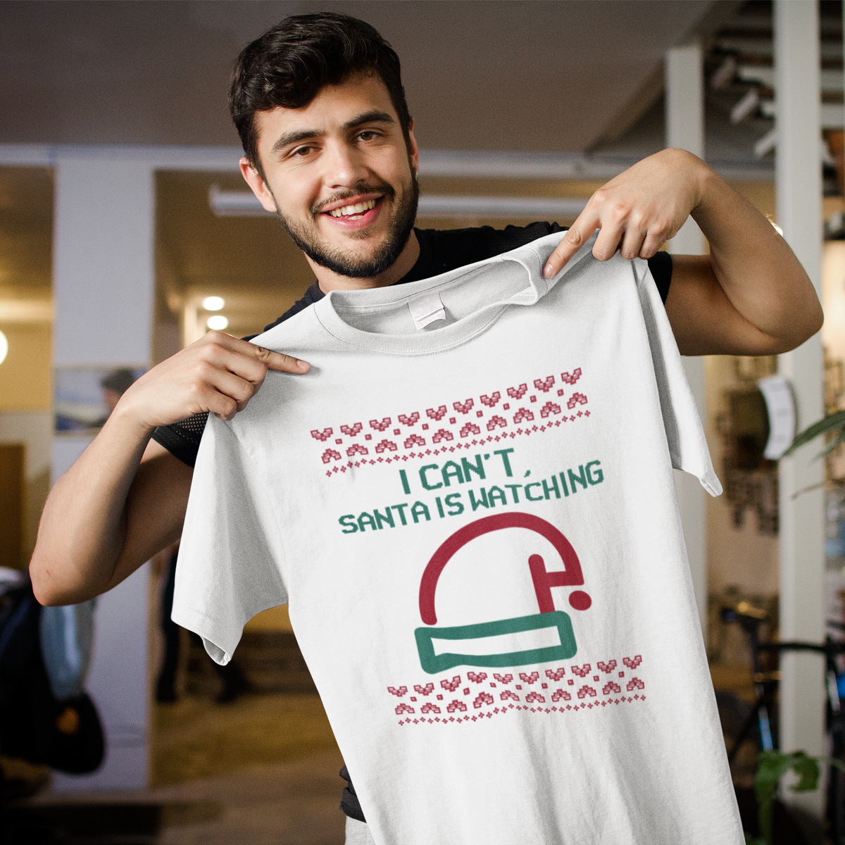 'I Can't Santa Is Watching' camera graphic t-shirt in white, man pointing at print, funny Christmas t-shirt gift