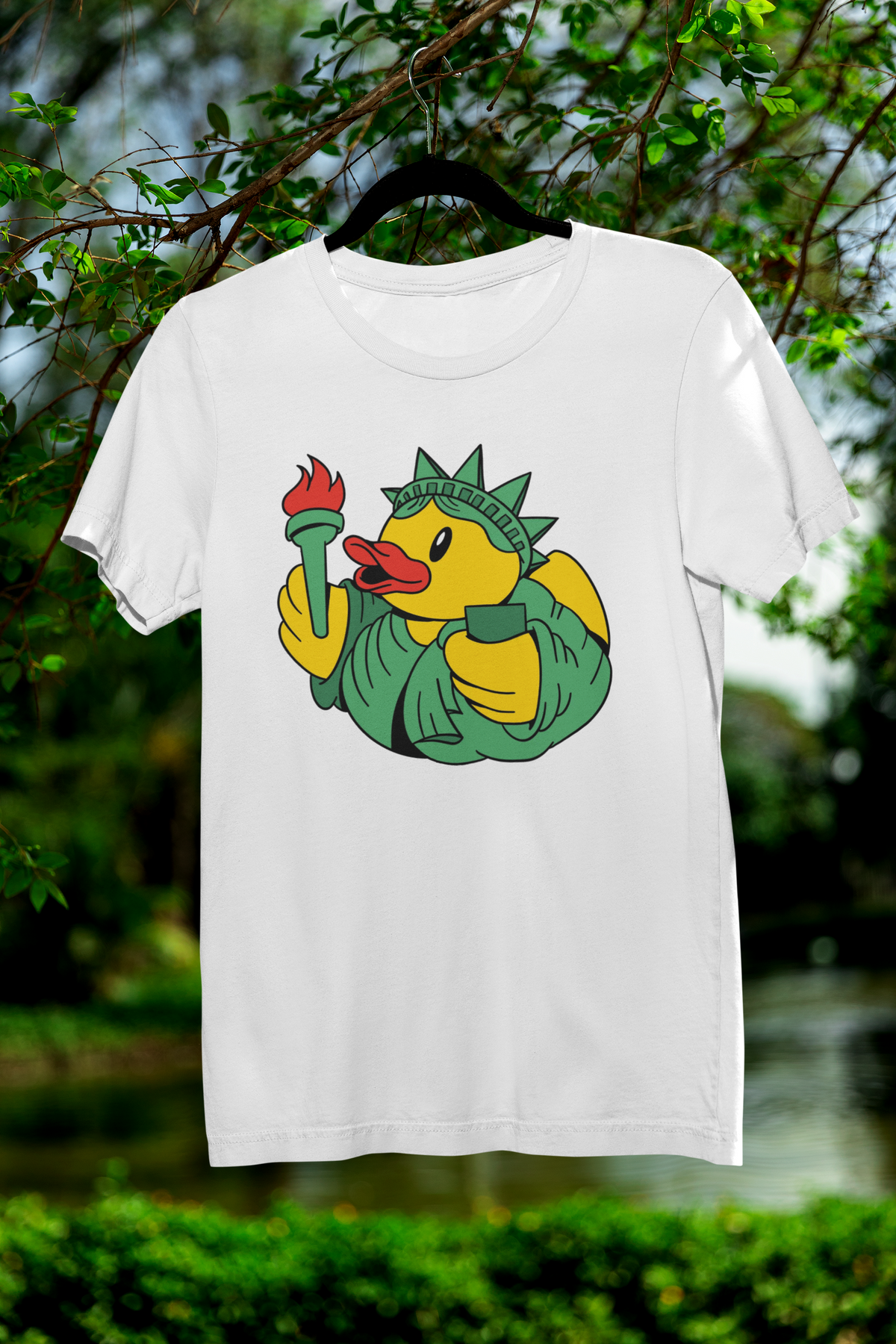 Liberty duck t-shirt in white, hanging outdoors among green trees, funny americana animal gift