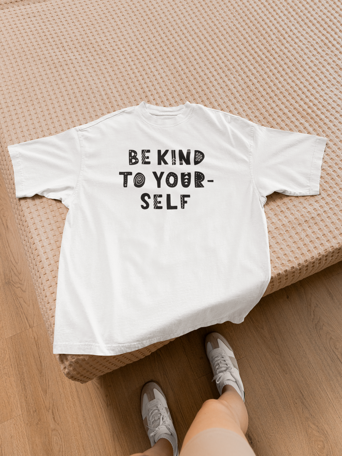 Be Kind To Yourself t-shirt in white, flat lay back view on a bed