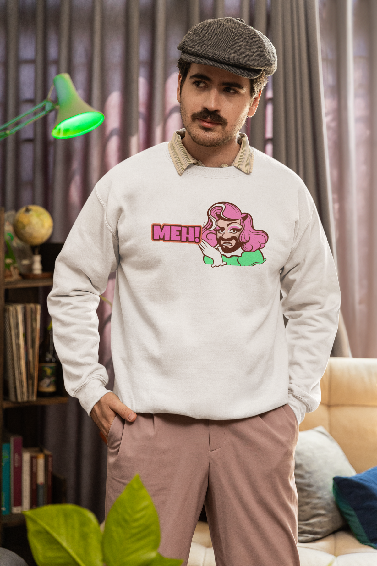 'MEH!' funny pink haired character sweatshirt in cream, man wearing it indoors, quirky sarcastic gift
