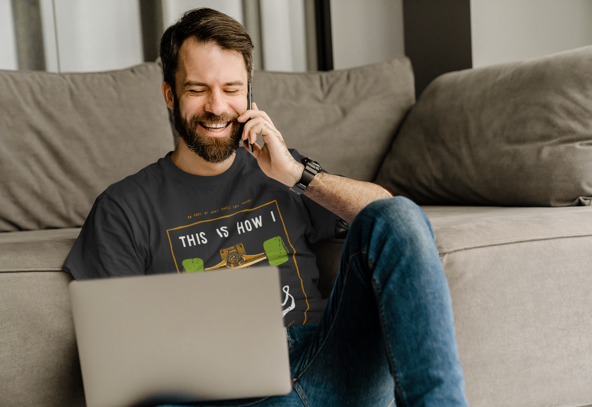 "This Is How I Roll" skateboard t-shirt in black, man wearing it on sofa, funny gift for skaters