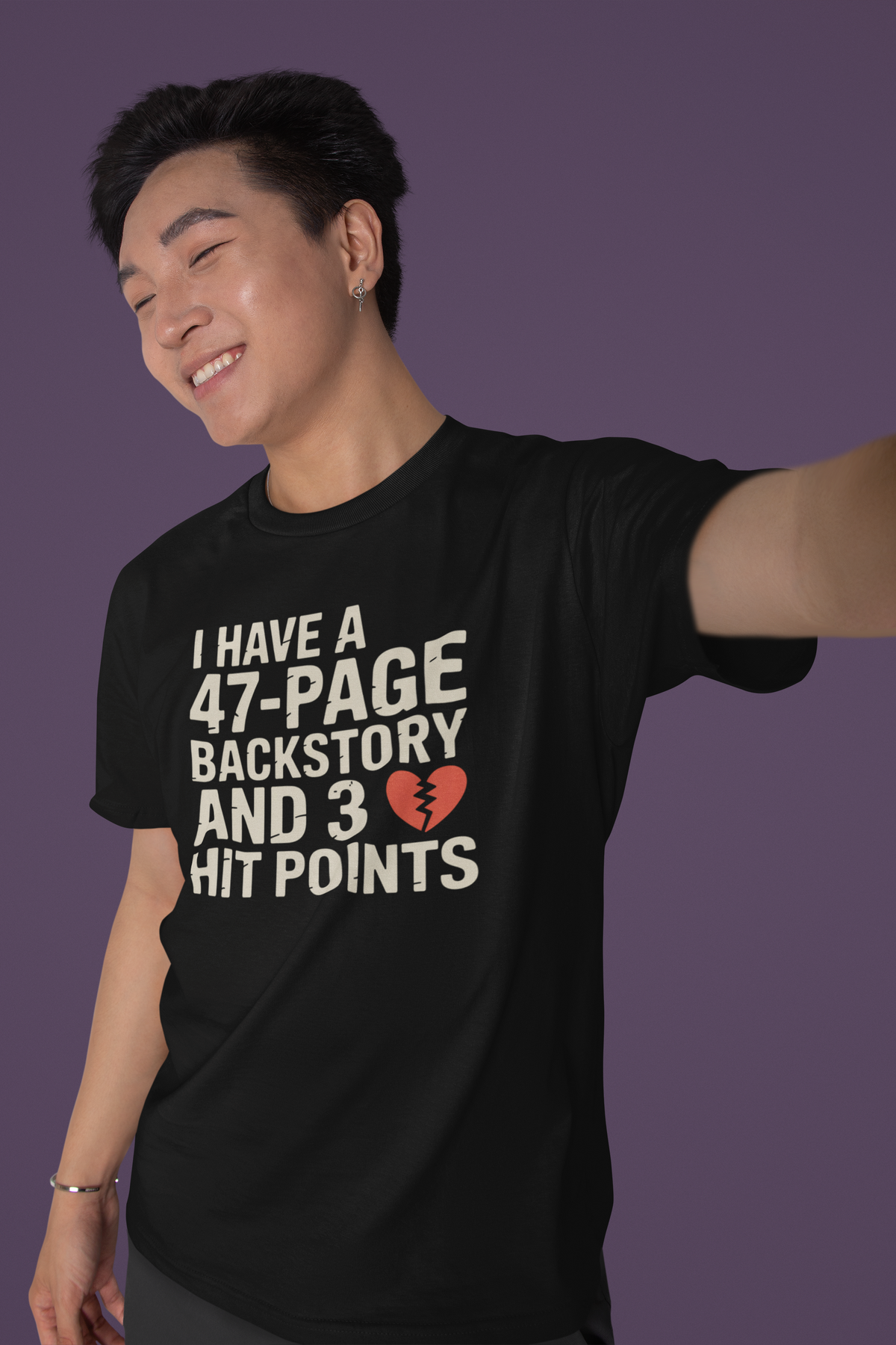 'I Have a 47-Page Backstory and 3 Hit Points' black tee worn by smiling man on purple backdrop, gift