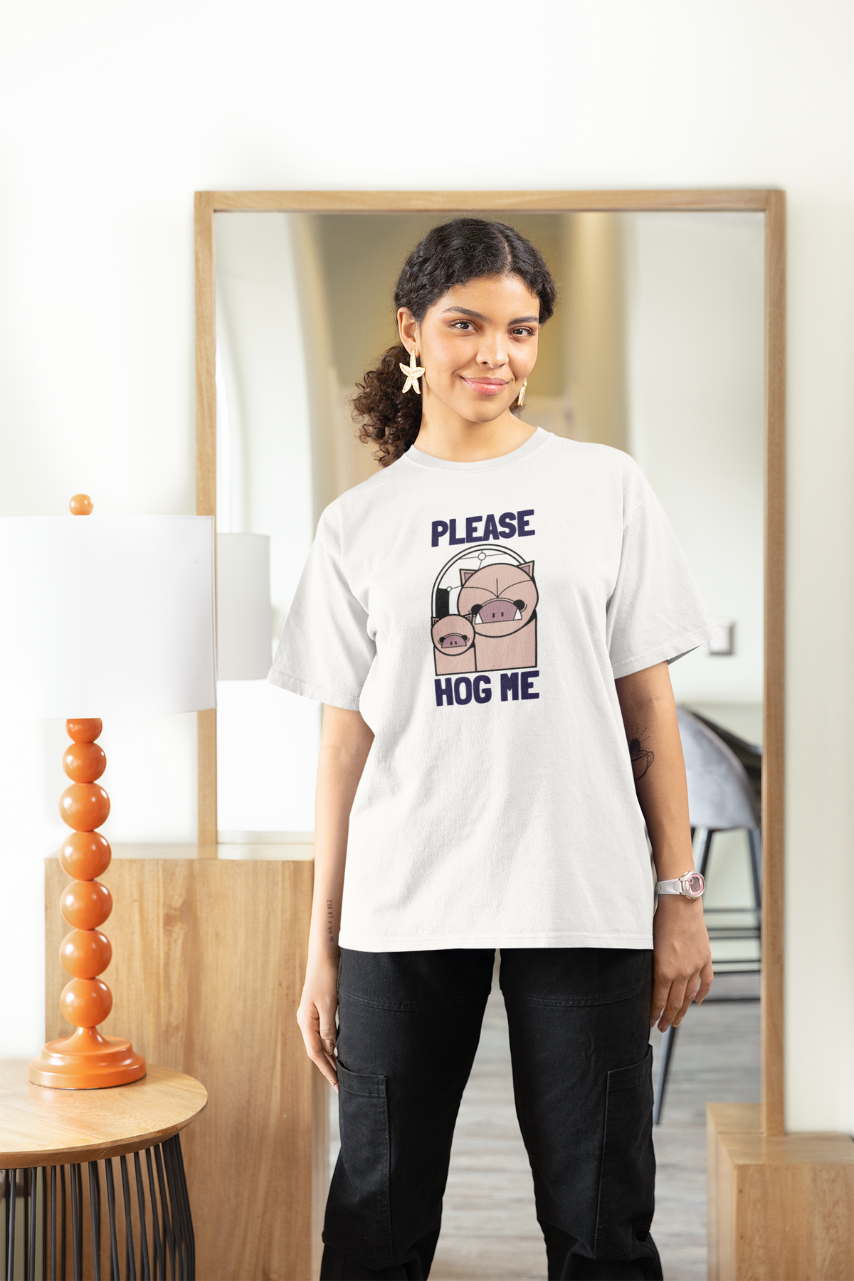 'Please Hog Me' pig graphic women's tee in white, woman wearing it indoors, funny pig pun gift idea