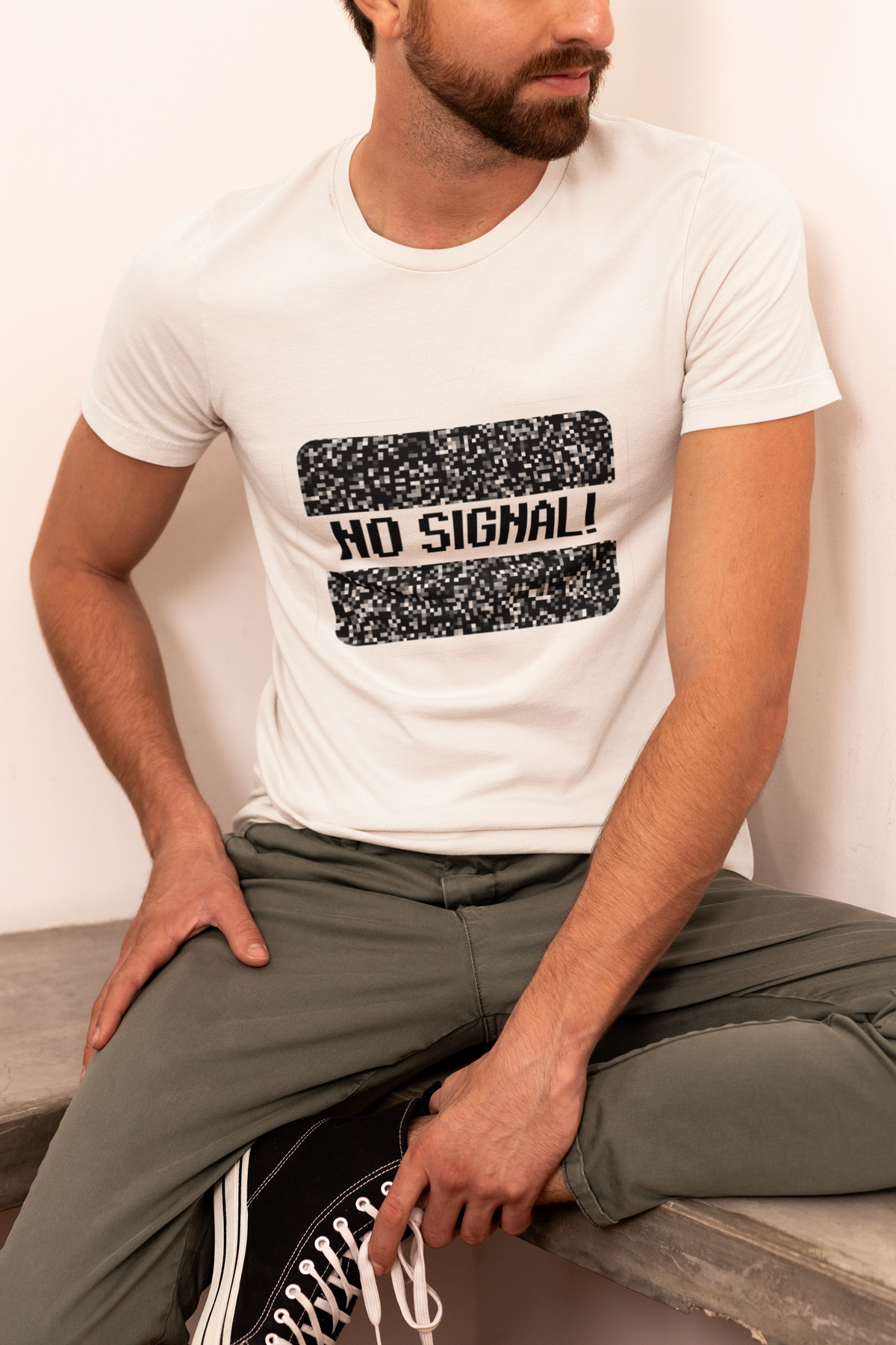 'No Signal' graphic t-shirt in white, man wearing it seated, funny retro TV shirt for gamers