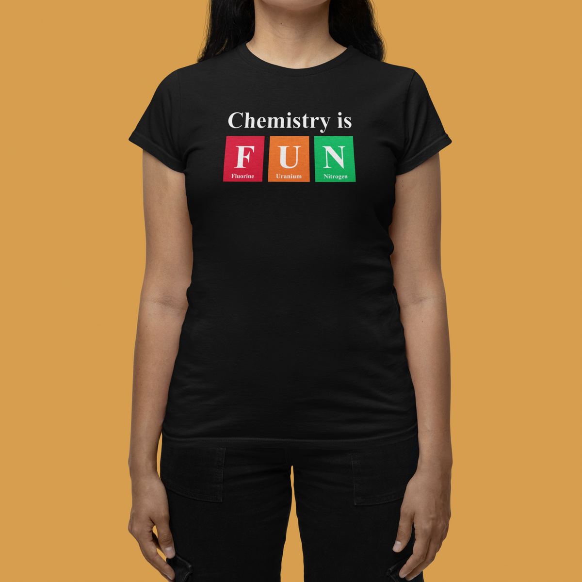 'Chemistry is FUN' women's fitted t-shirt in black, woman wearing it against orange backdrop, funny chemistry pun gift