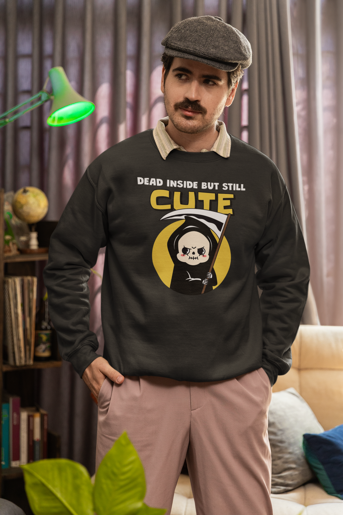 'Dead Inside but Still Cute' sweatshirt in black, man wearing it in a cozy study, funny goth pun crewneck gift