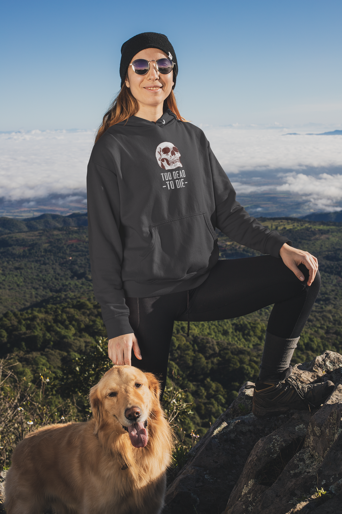 'Too Dead To Die' skull graphic hoodie in black, woman wearing it hiking with her dog, gothic gift