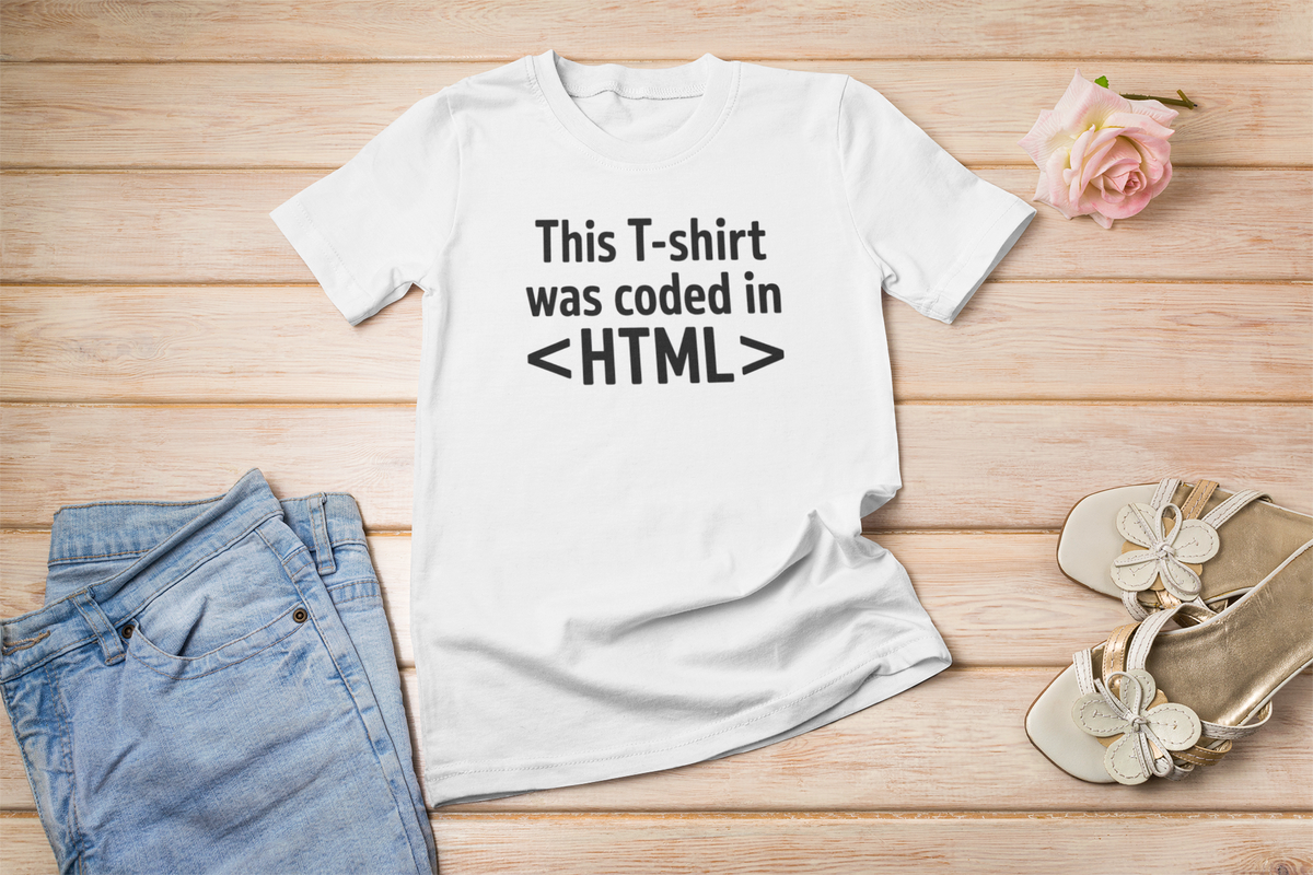 'This T-shirt was coded in HTML' white tee flat lay on wood with jeans and sandals, funny programmer gift