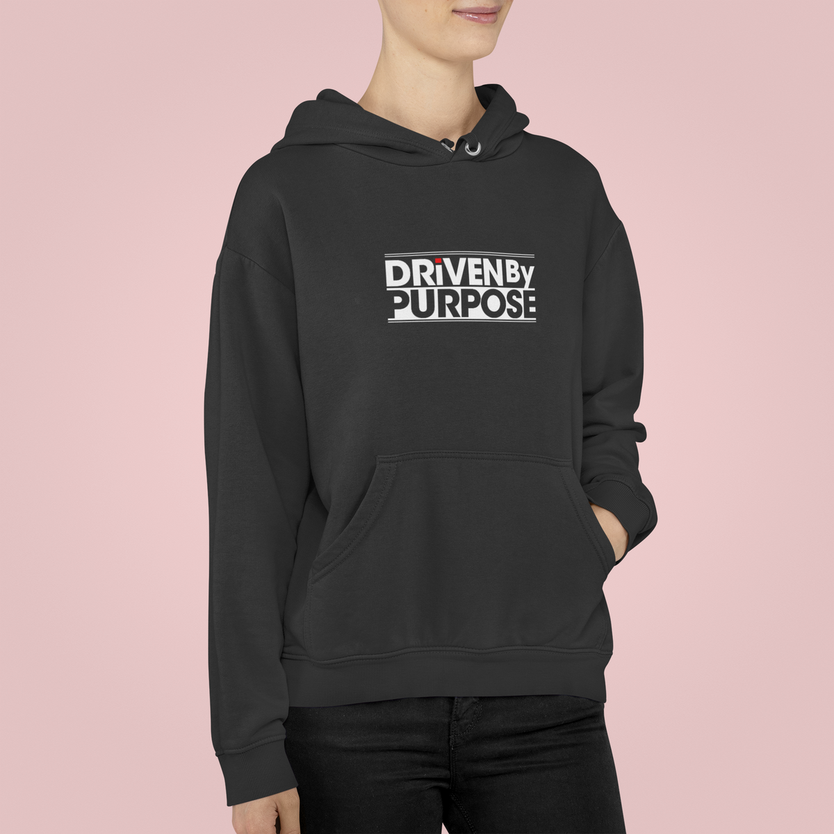 Driven by Purpose Hoodie in black, woman wearing it against a pink backdrop, motivational streetwear gift