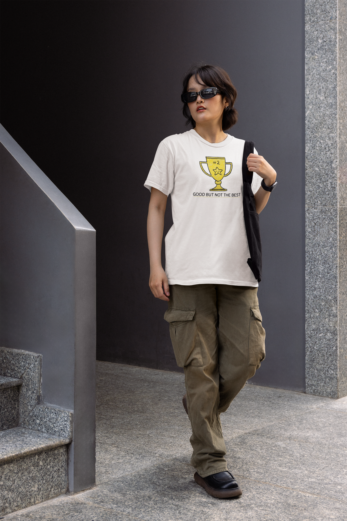 'Good But Not the Best' trophy tee in white, man walking in cargo pants, urban street style, funny graphic tee